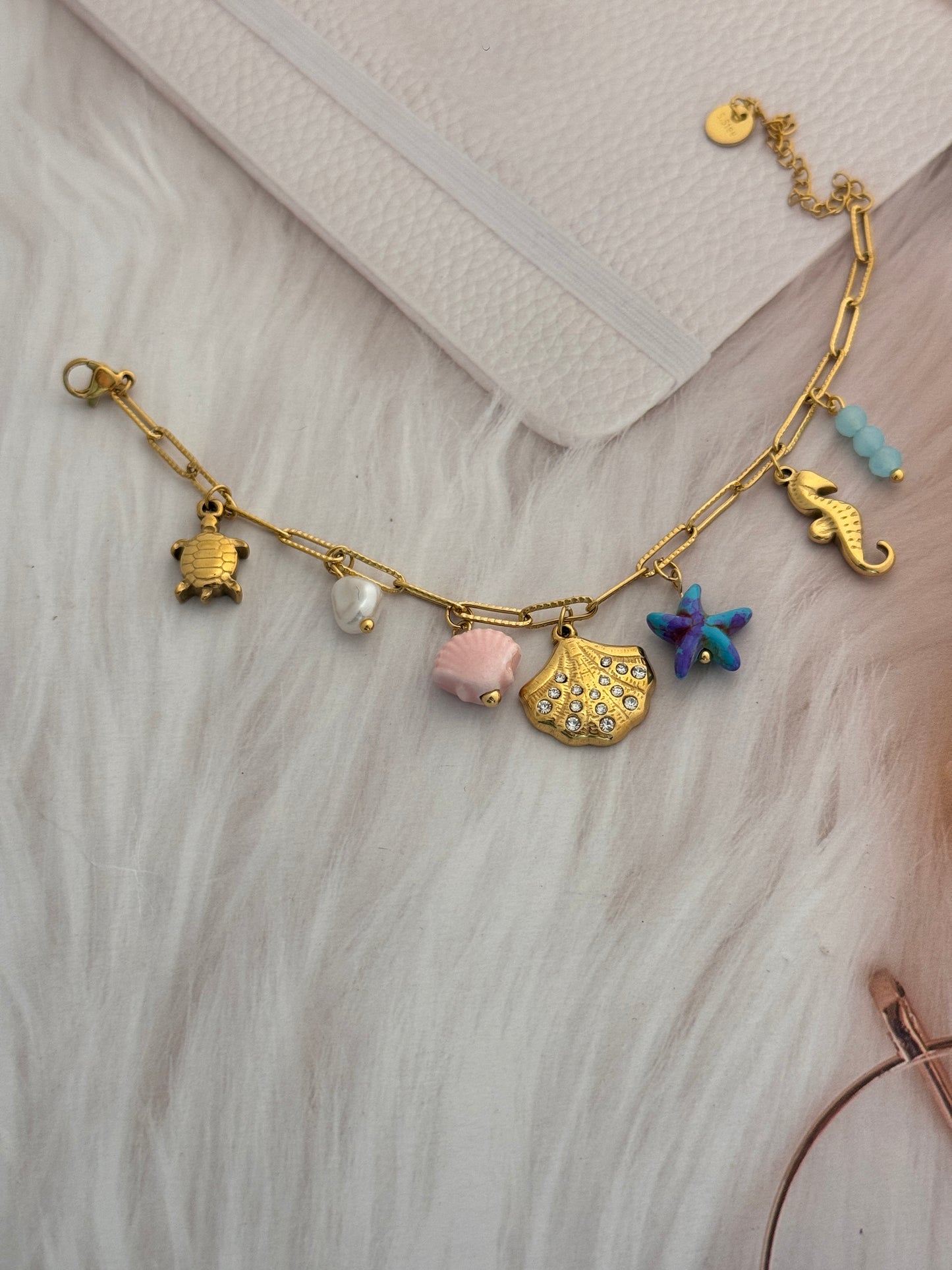 Gold bracelet with various charms on a light wooden surface