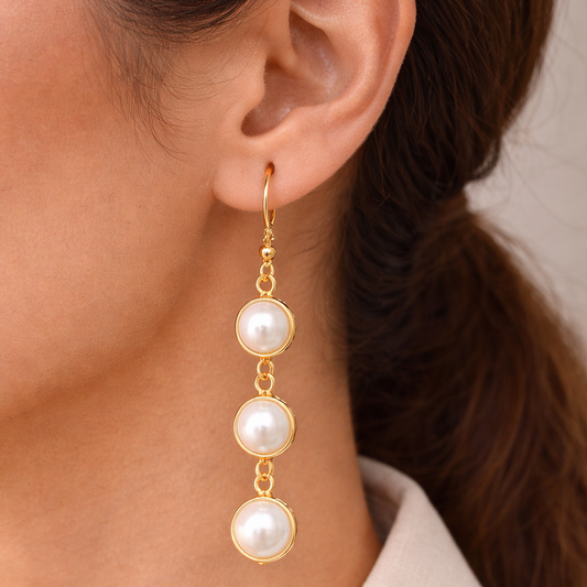 Pearl earrings with gold hooks worn by a person