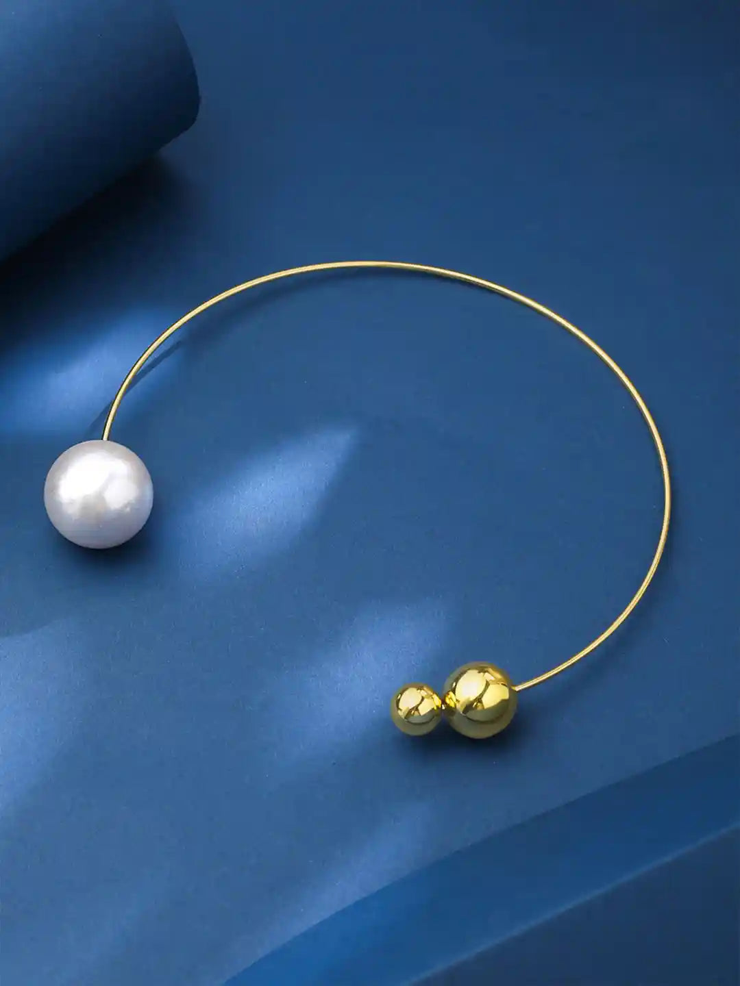 Gold necklace with a pearl and gold beads on a blue background