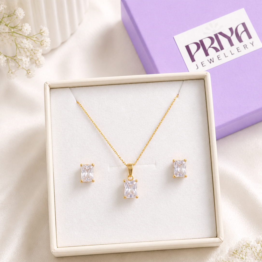 Gold necklace and earrings set in a box with a Pray Jewellery box in the background.