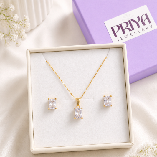 Gold necklace and earrings set in a box with a Pray Jewellery box in the background.