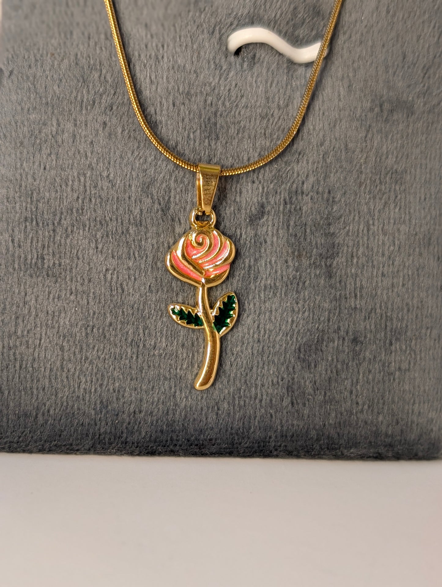 Gold necklace with a rose pendant on a gray background