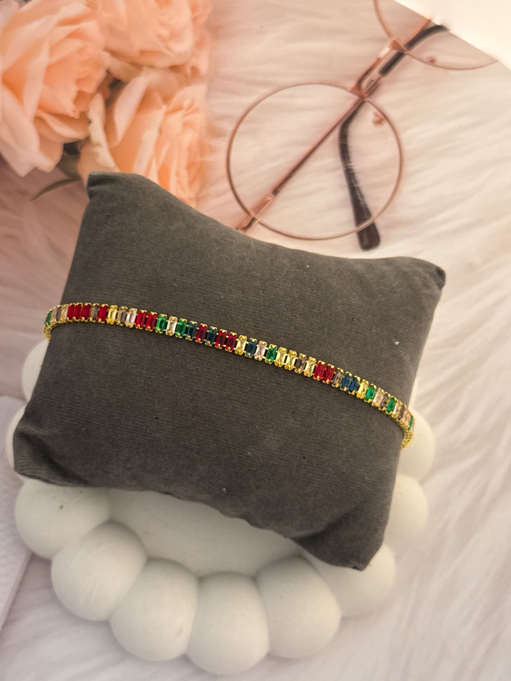 Multicolored beaded bracelet on a gray pillow with floral and decorative background