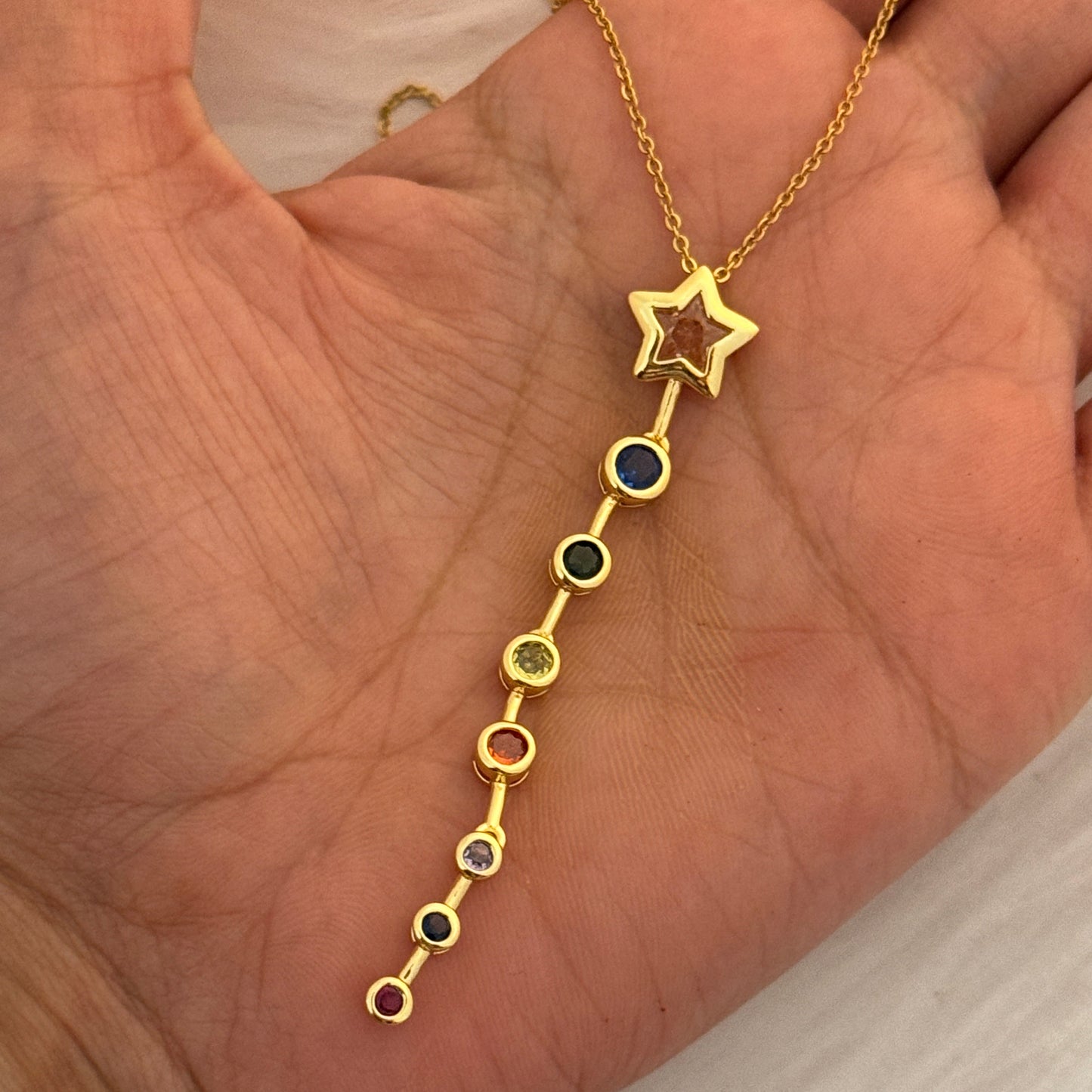 Gold bracelet with star and gemstone details held in a hand.