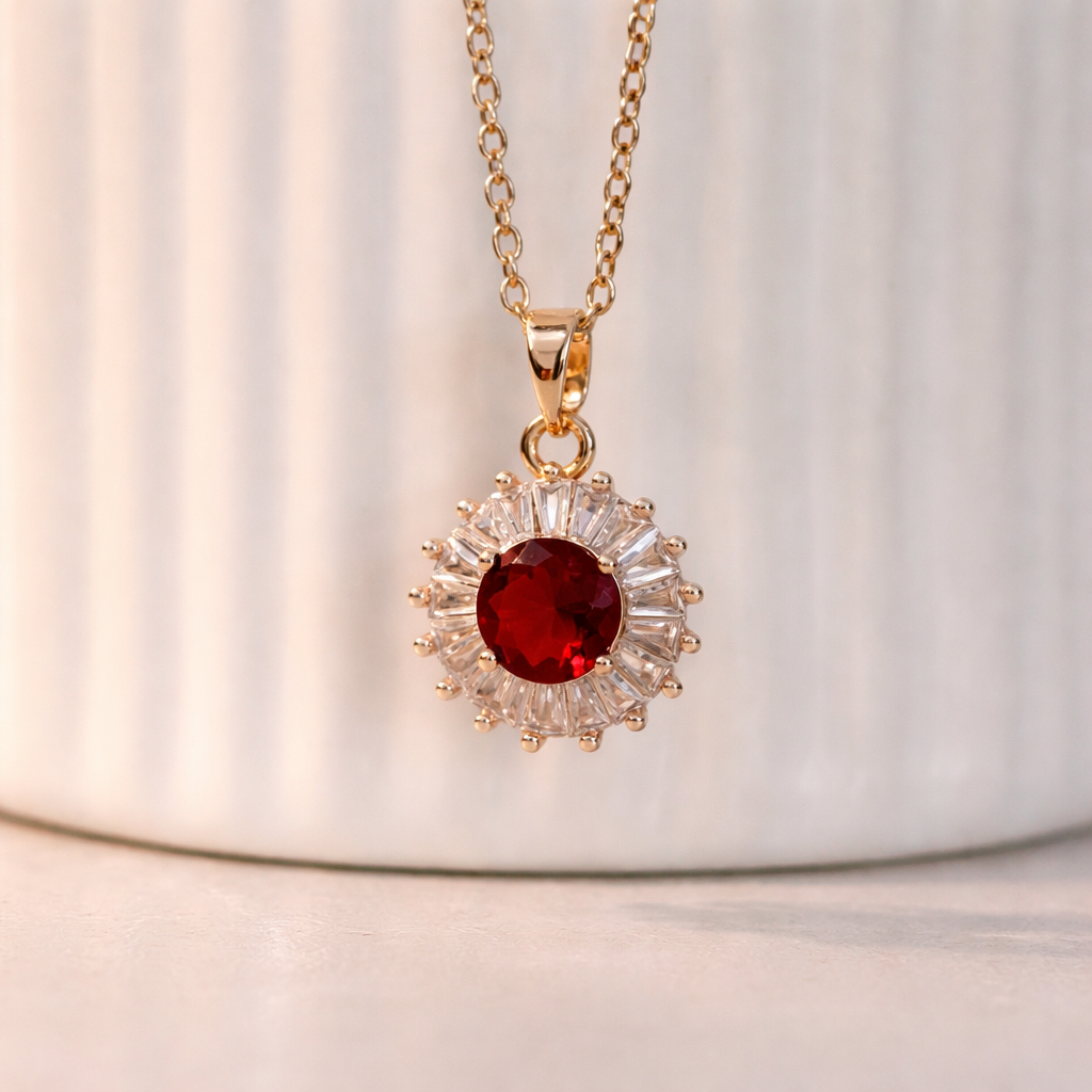 Gold necklace with a red gemstone pendant on a white background