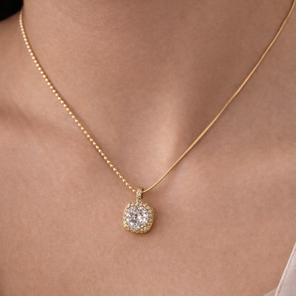 Gold necklace with a diamond pendant on a person wearing a beige top.