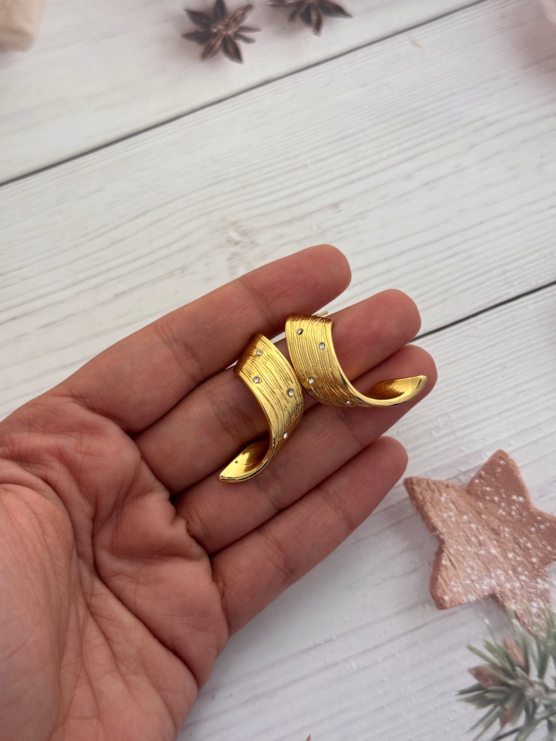 Gold ring on a hand with a wooden surface and star anise in the background
