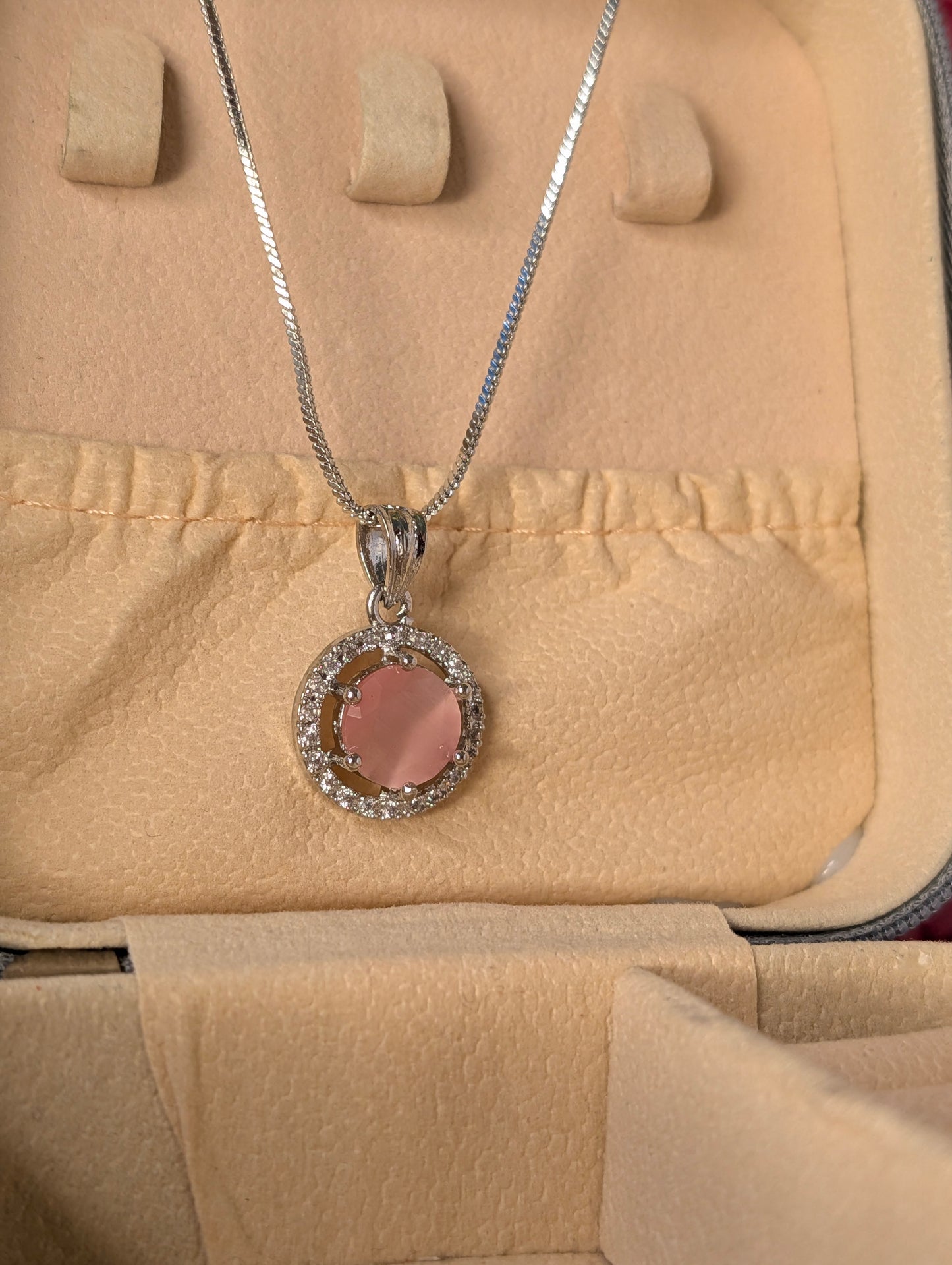 Silver necklace with a pink pendant on a beige jewelry box