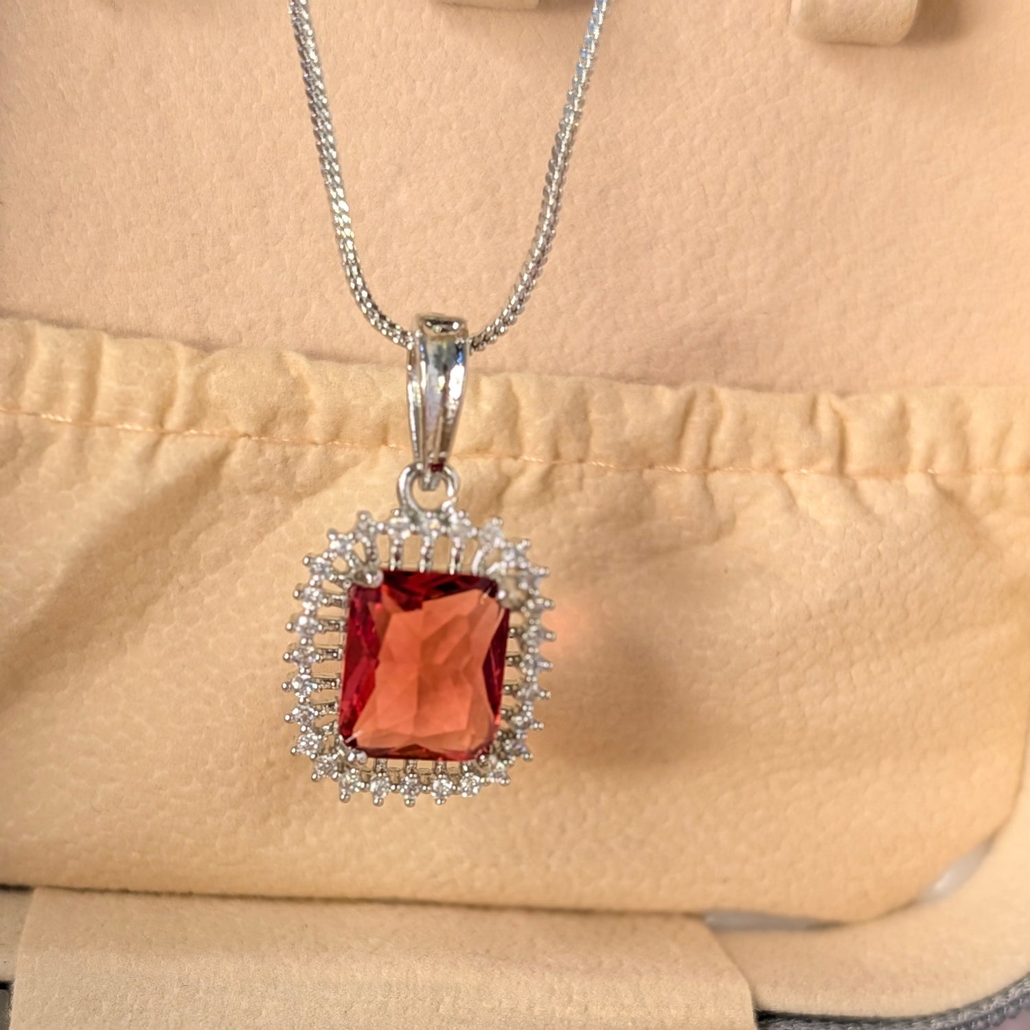 Silver pendant with a red gemstone on a beige background