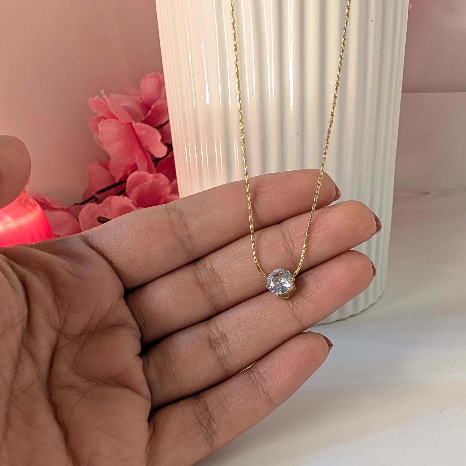 Gold necklace with a heart pendant held in a hand against a blurred background