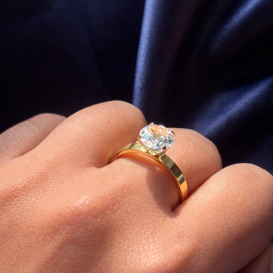 Gold ring with a diamond on a person's finger against a dark background