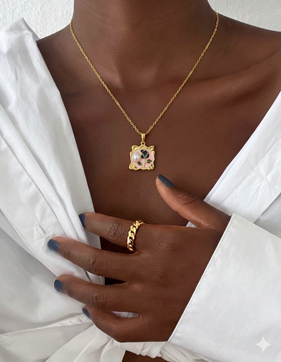 Gold necklace with a pendant worn by a person in a white outfit.