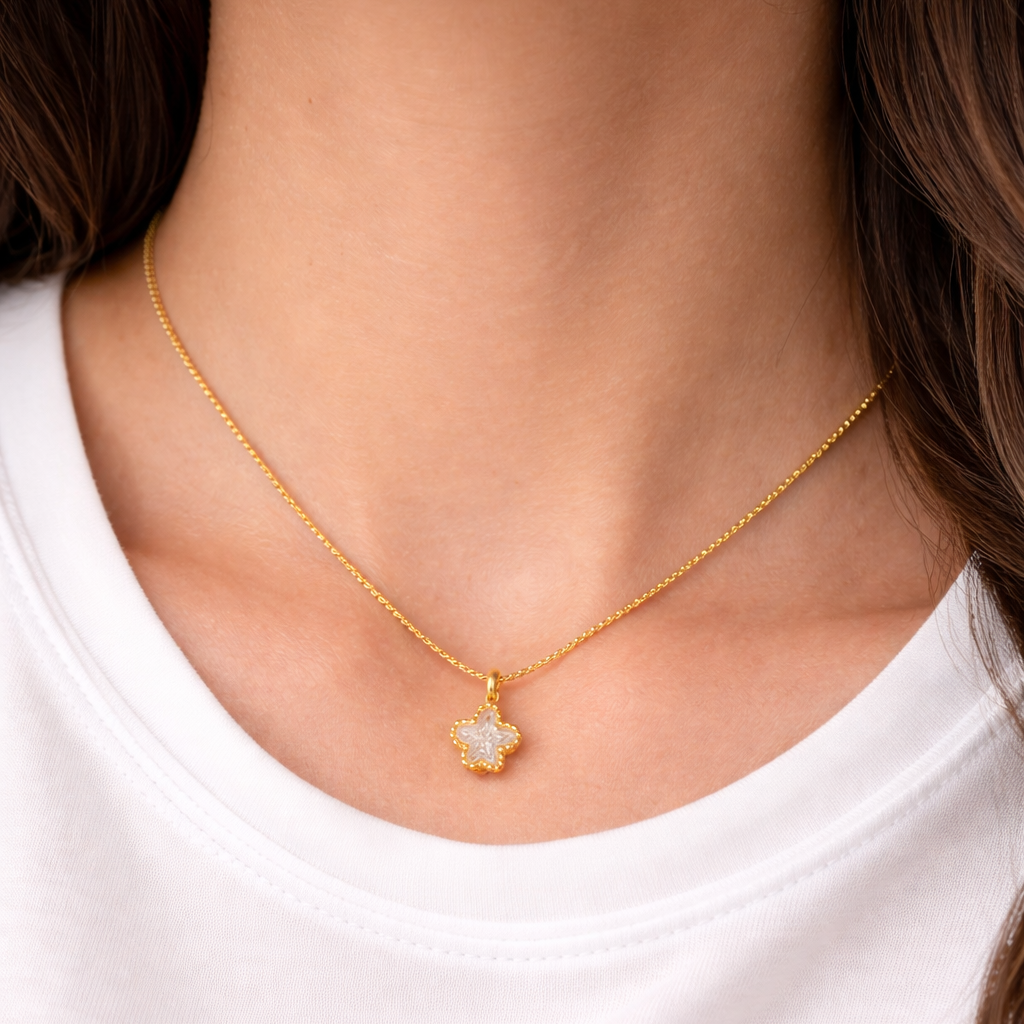Gold necklace with a star-shaped pendant worn by a person on a white background