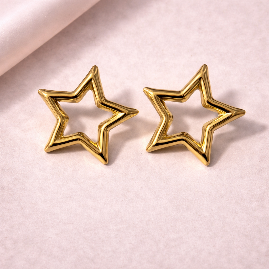 Gold star-shaped earrings on a light pink background