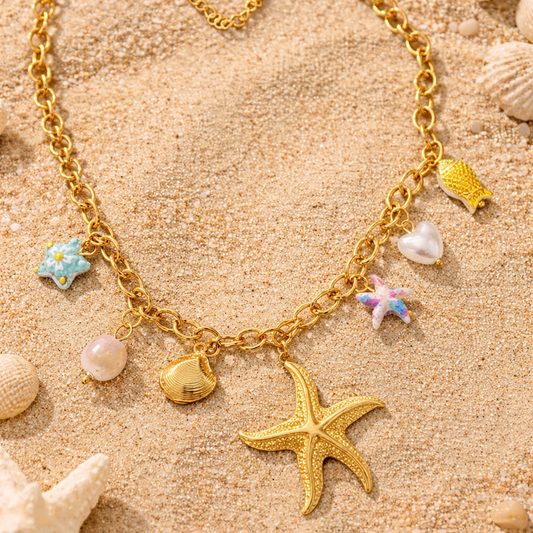 Gold bracelet with starfish charm on sand with starfish and shells