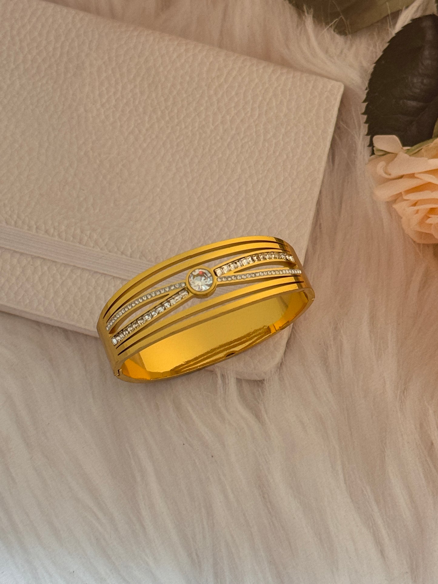 Gold bracelet with gemstones on a textured surface