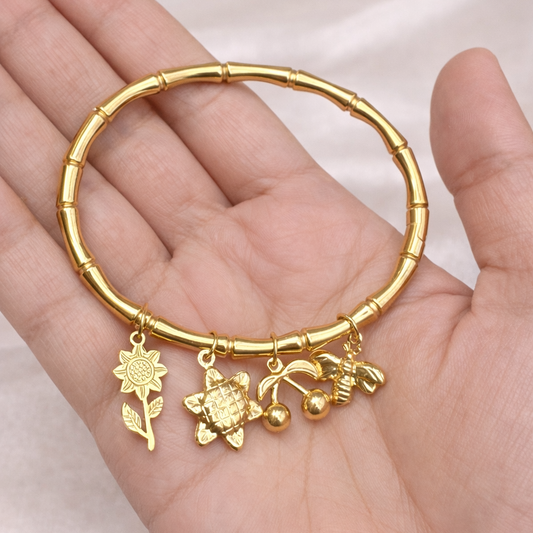 Gold bracelet with charms held in a hand on a light background