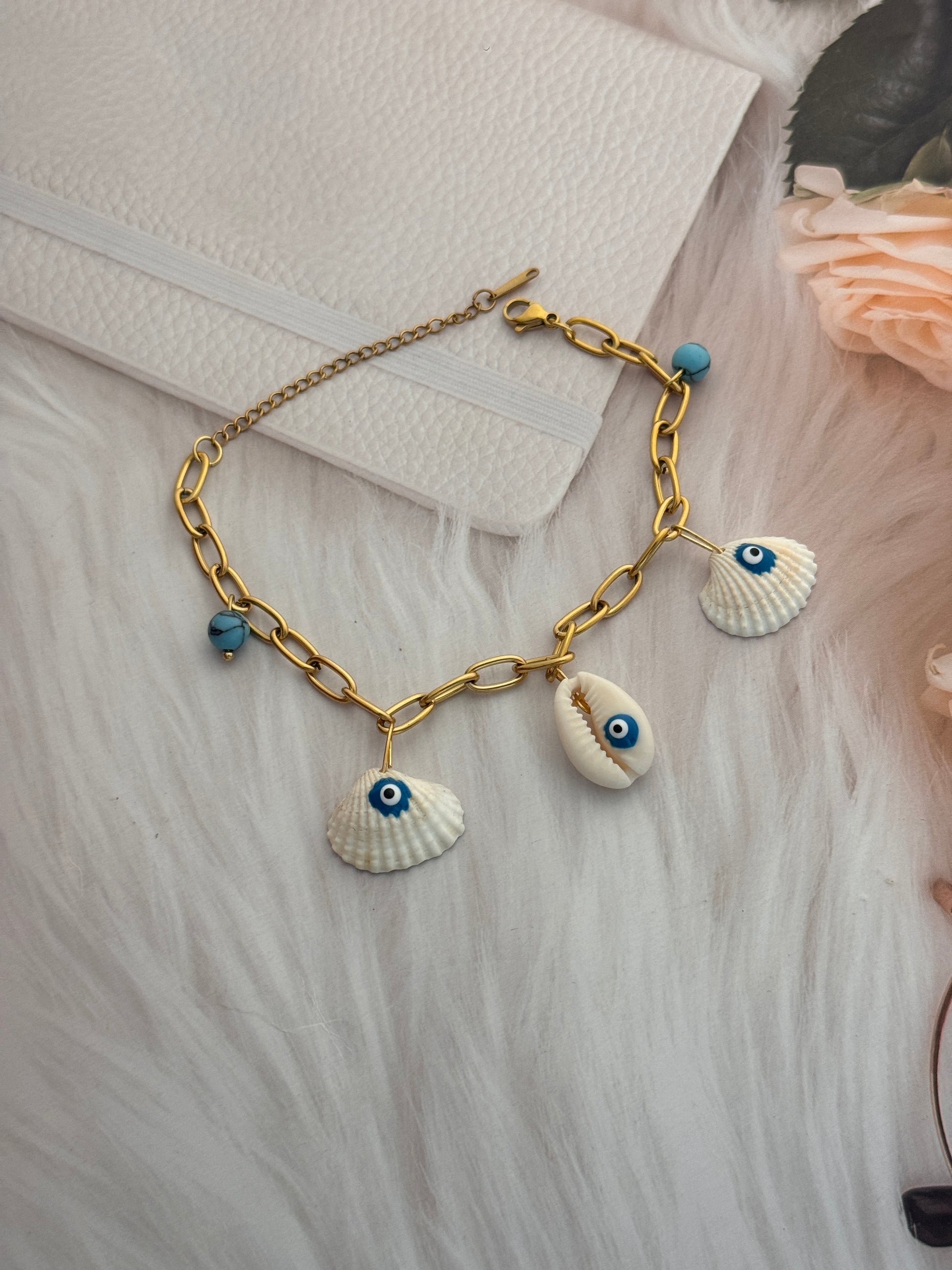 Bracelet with shell and eye charms on a textured surface