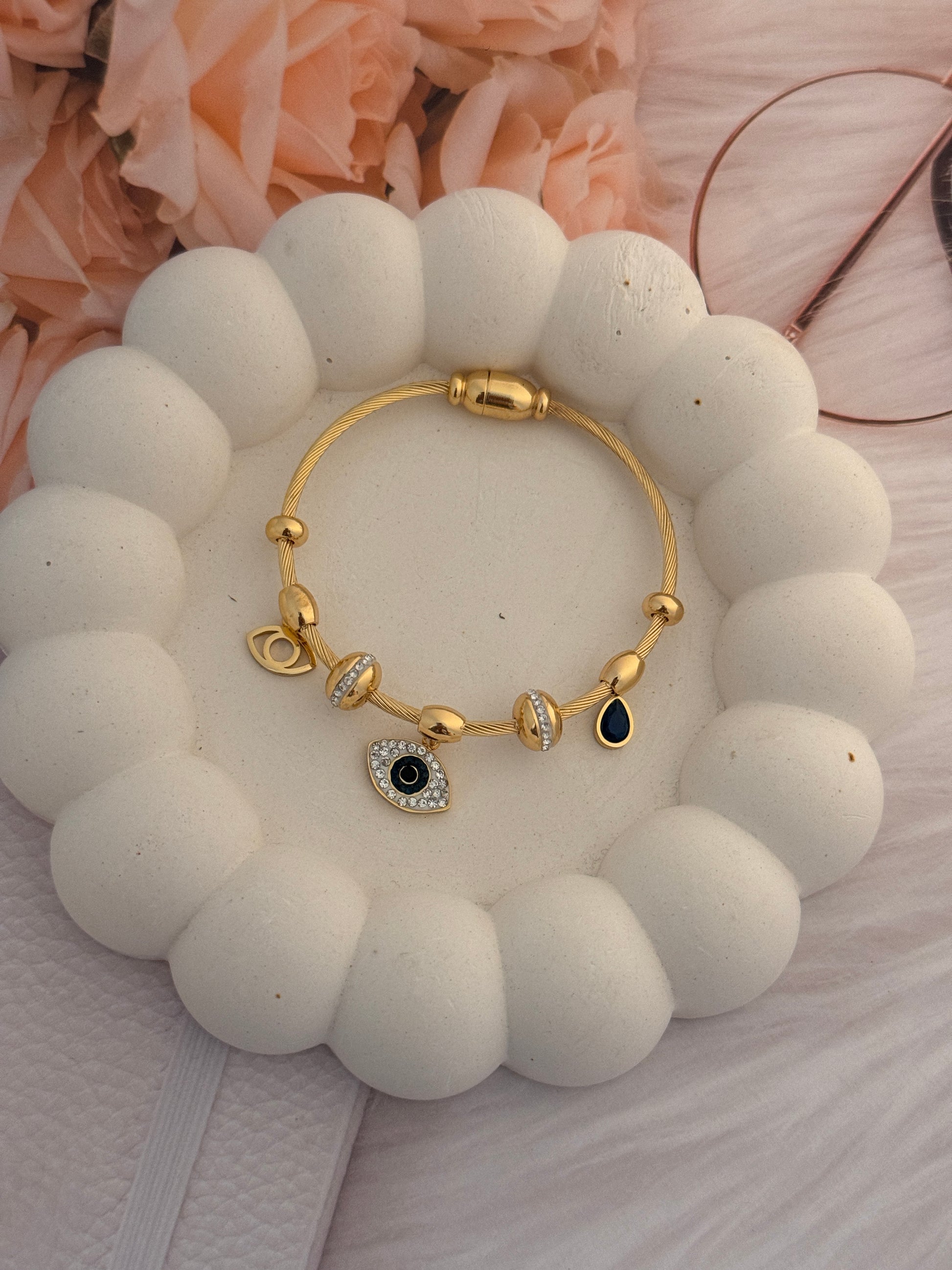 Gold bracelet with black stone on a white stone surface
