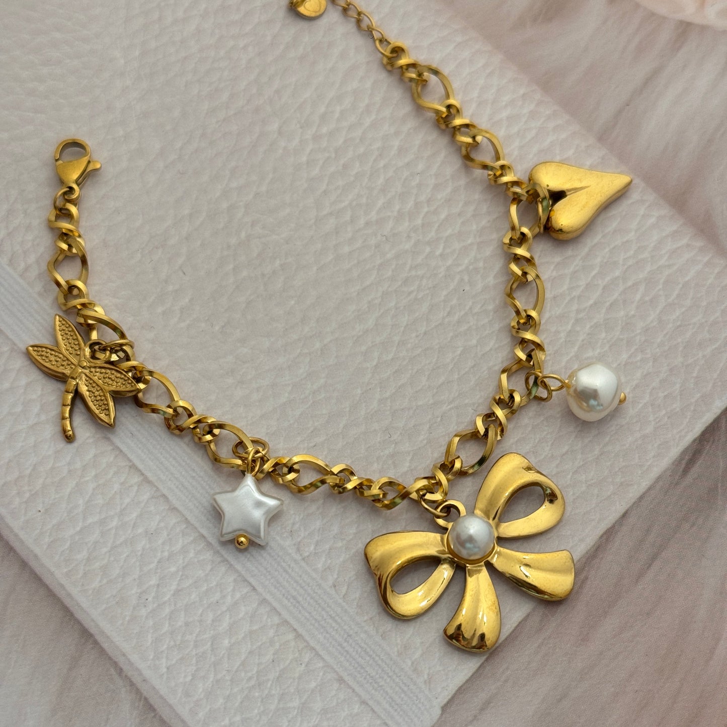 Gold bracelet with charms on a white fabric background