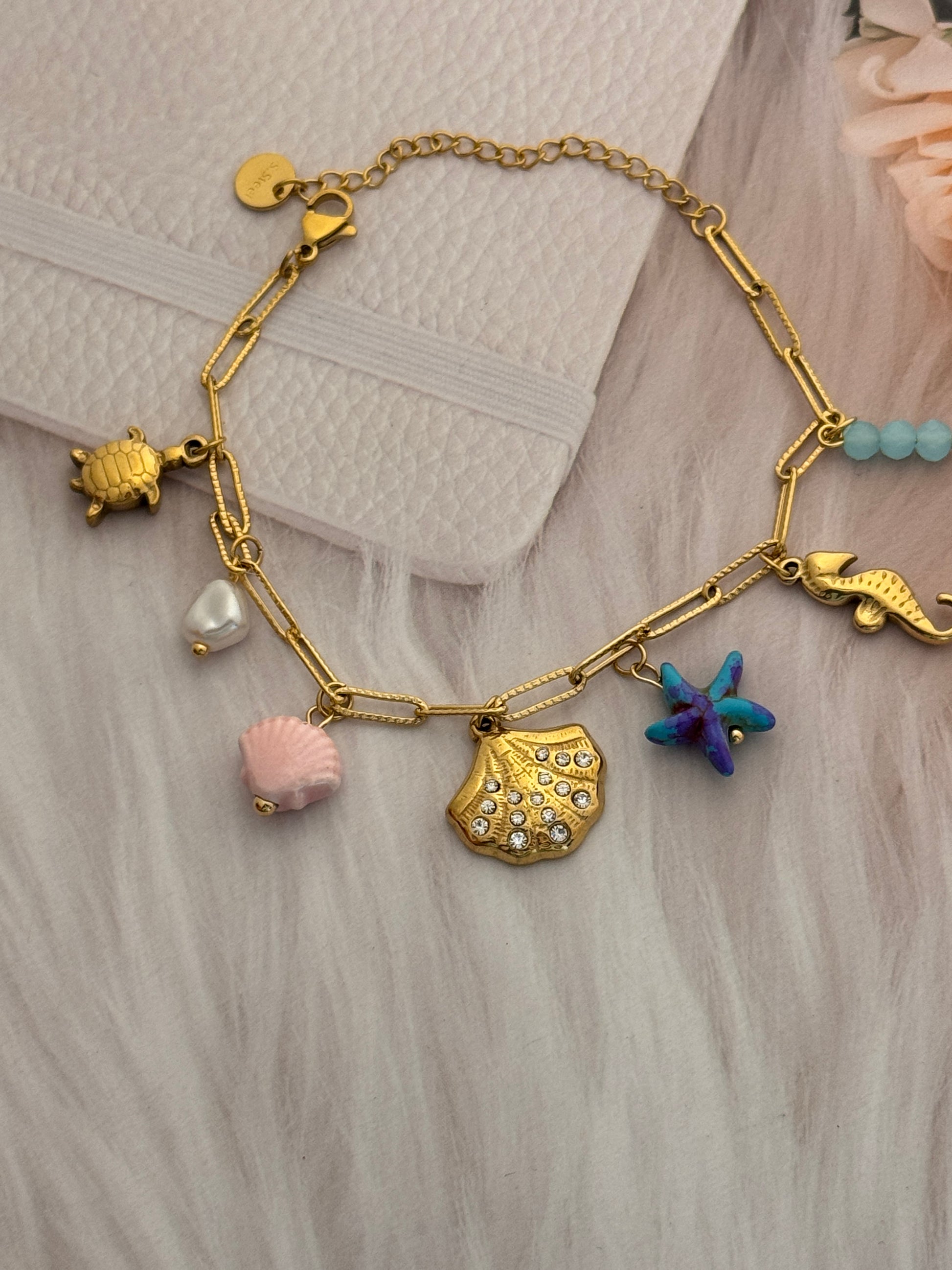 Gold bracelet with various charms on a textured surface