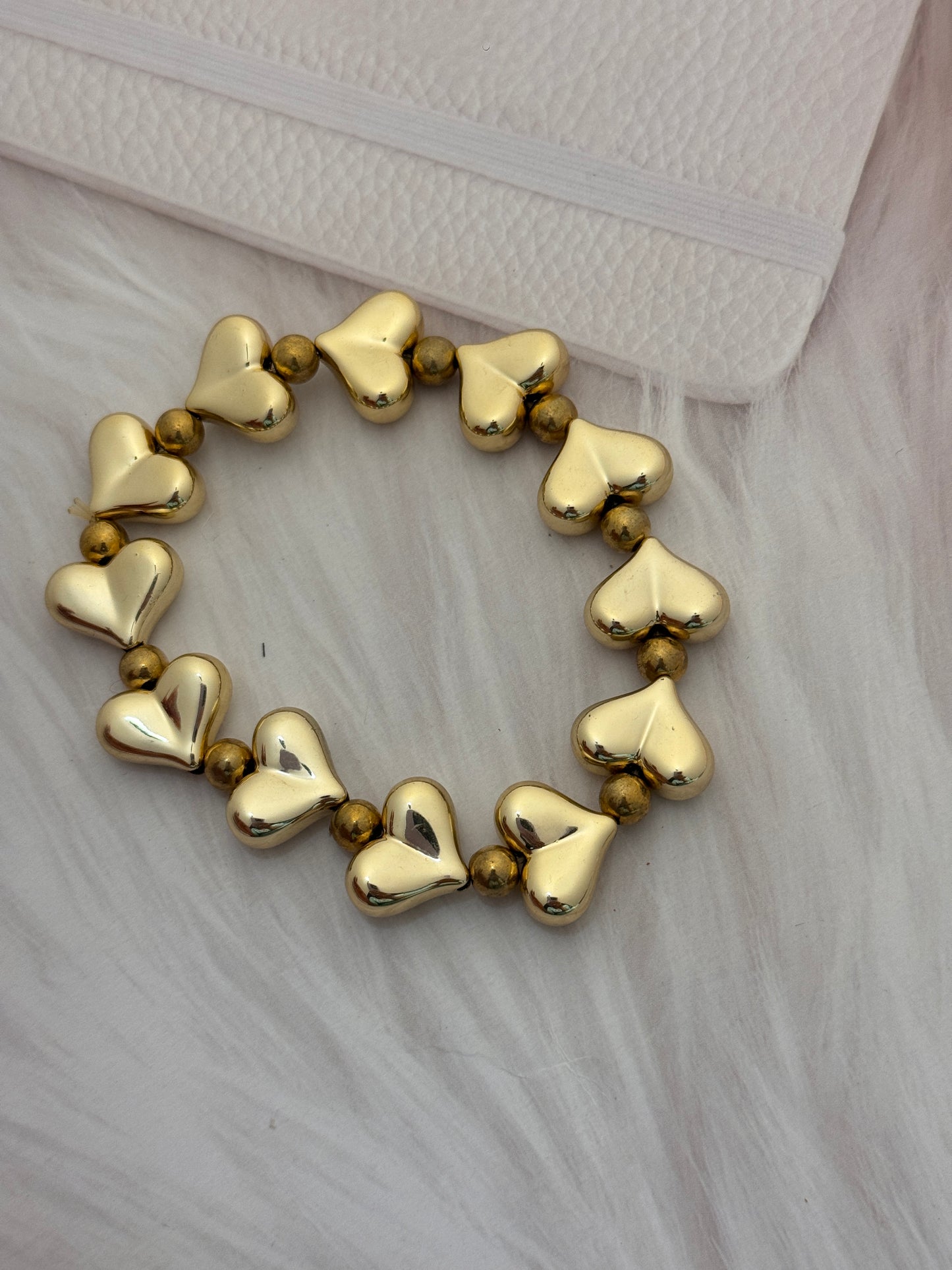 Gold heart-shaped beaded bracelet on a textured surface
