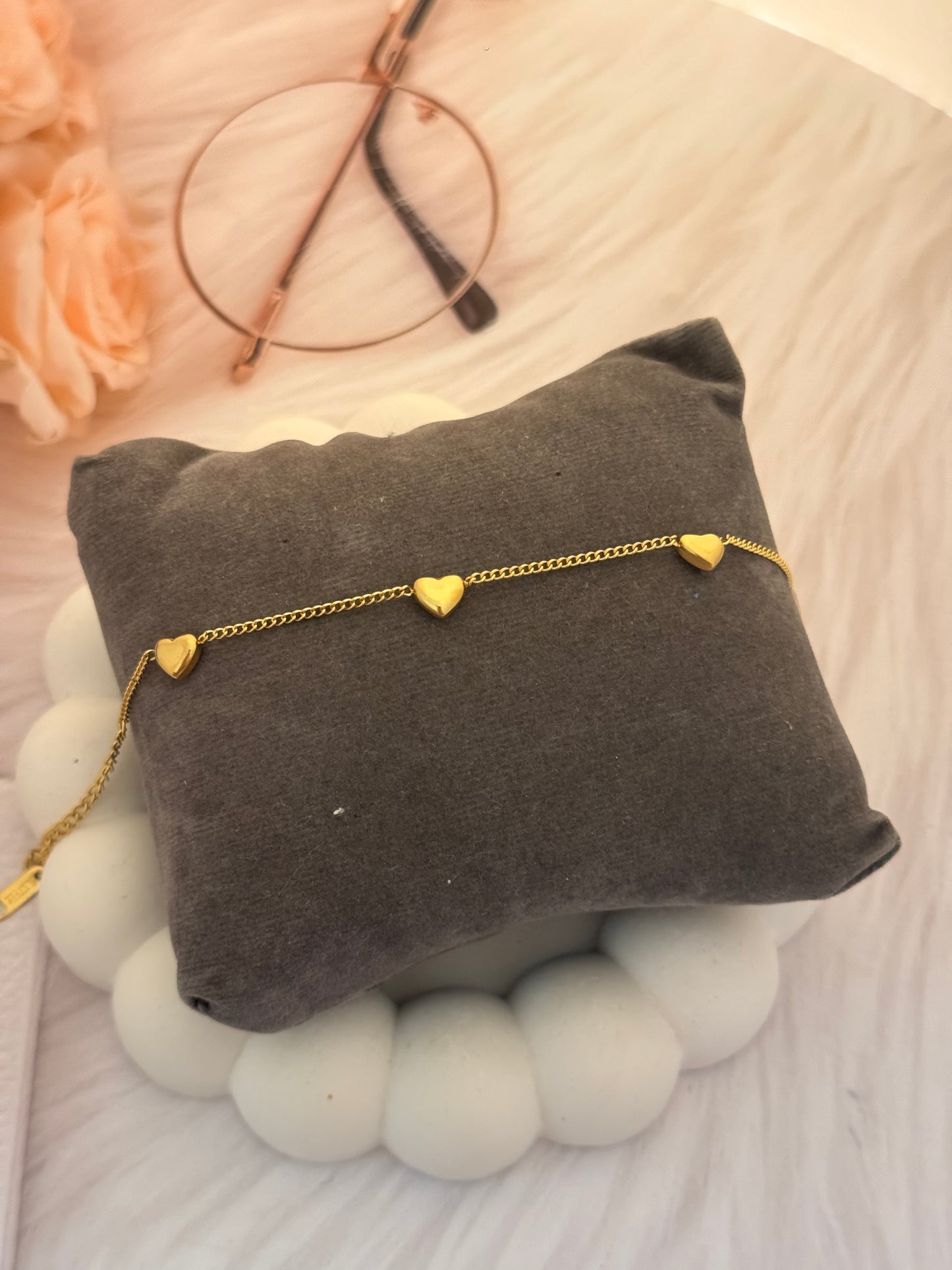 Gold bracelet on a gray cushion with a blurred background