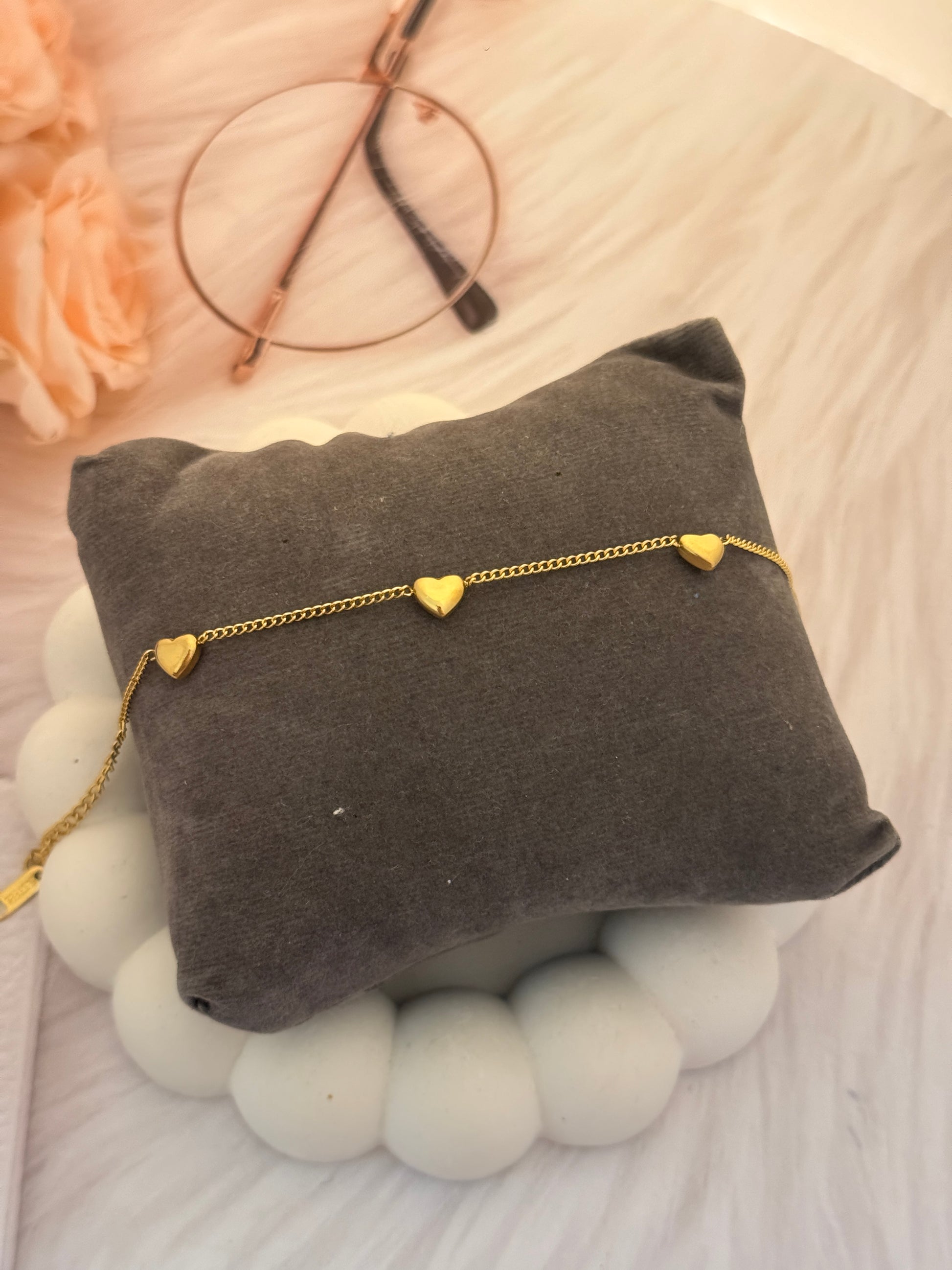 Gold bracelet on a gray cushion with a blurred background
