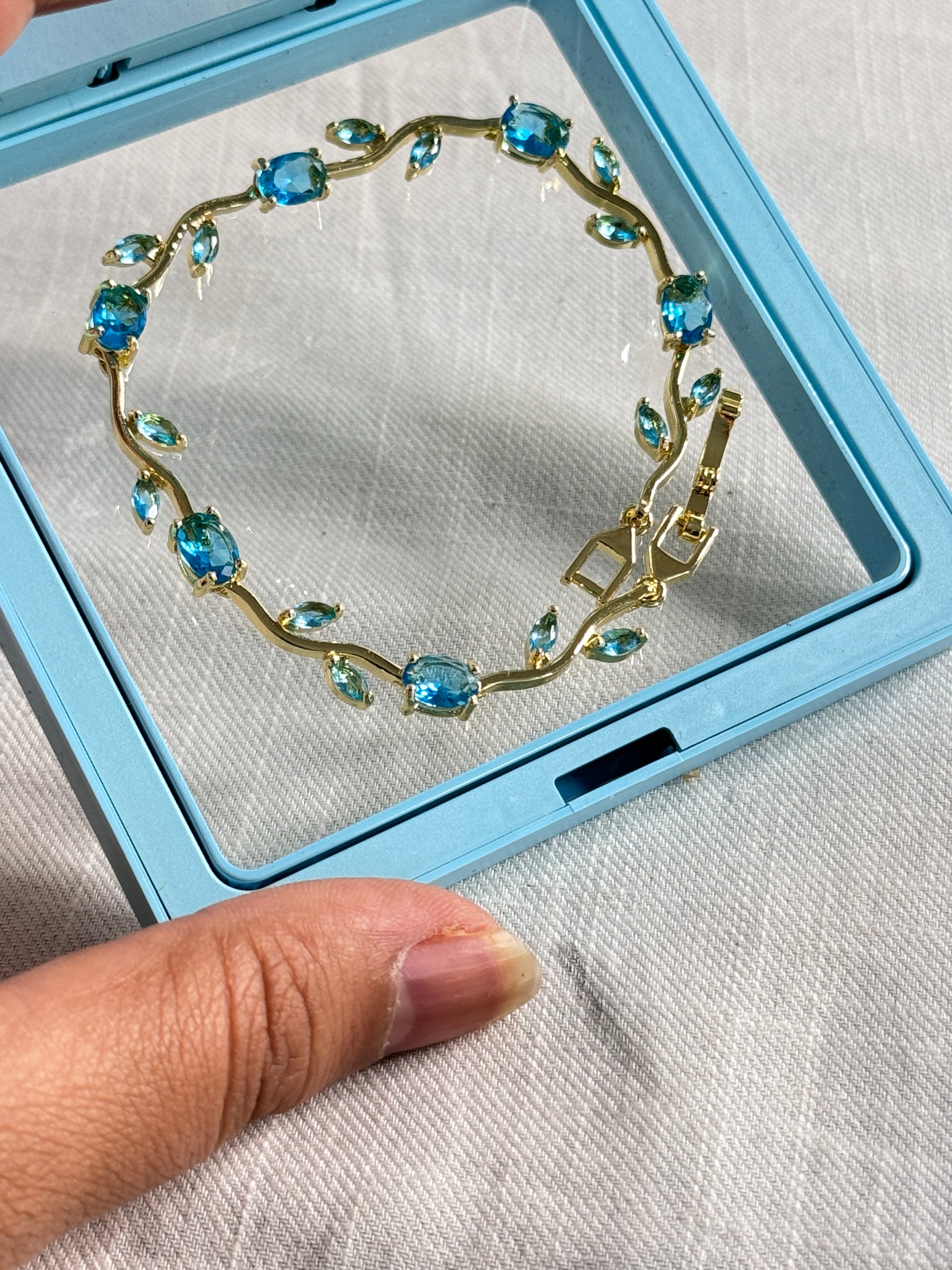 Bracelet with blue gemstones in a blue display case on a white fabric background