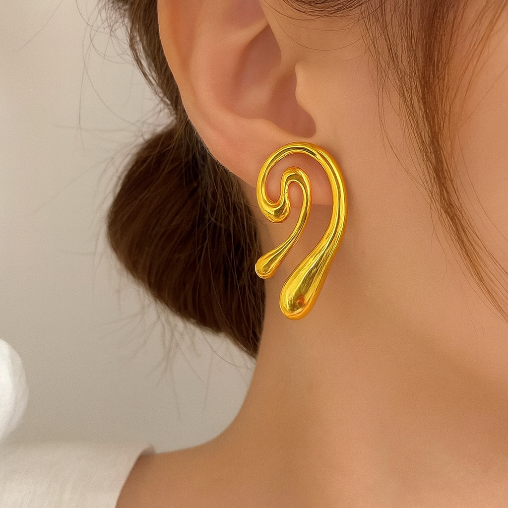 Gold spiral earring worn by a person with a neutral background