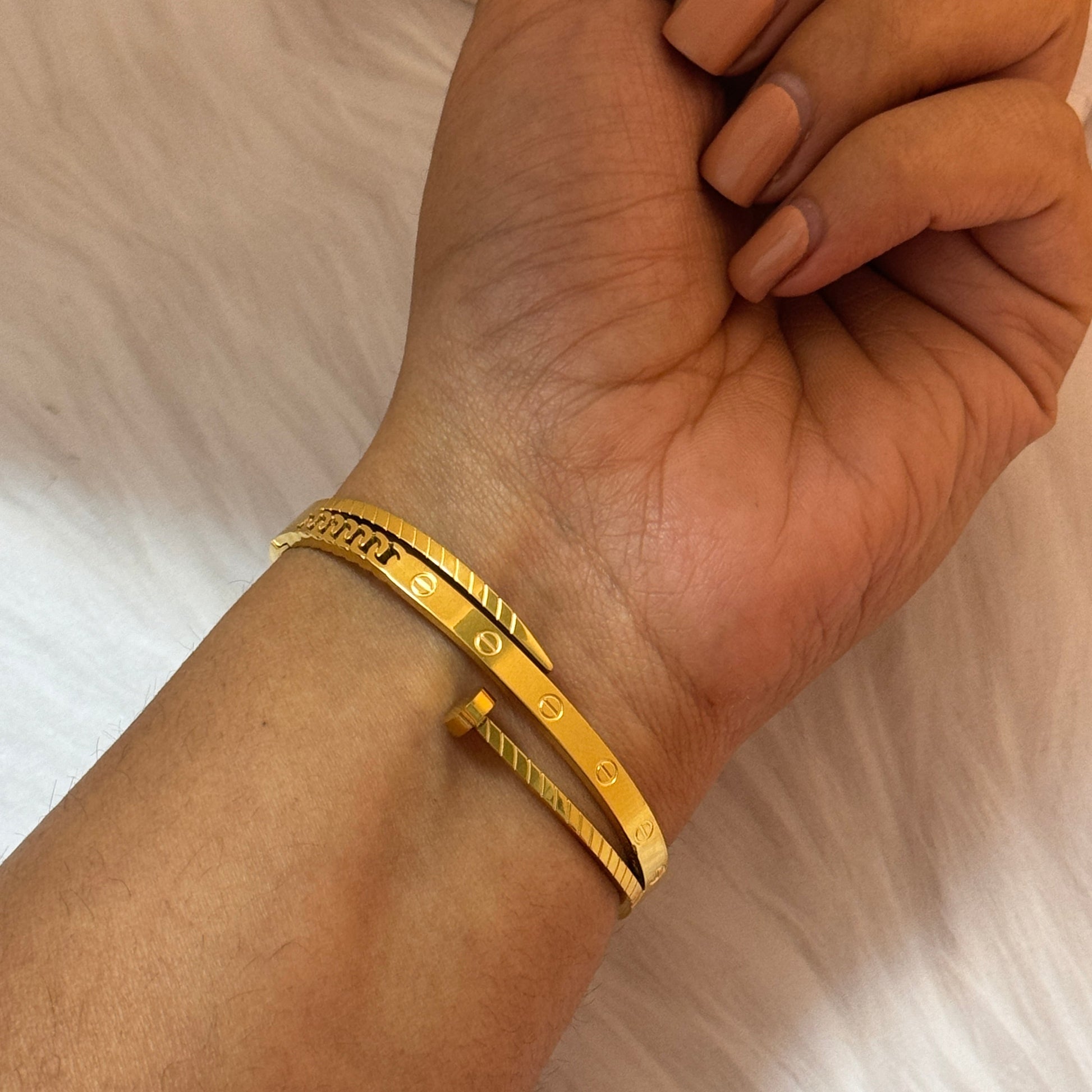 Gold bracelet on a wrist with a neutral background