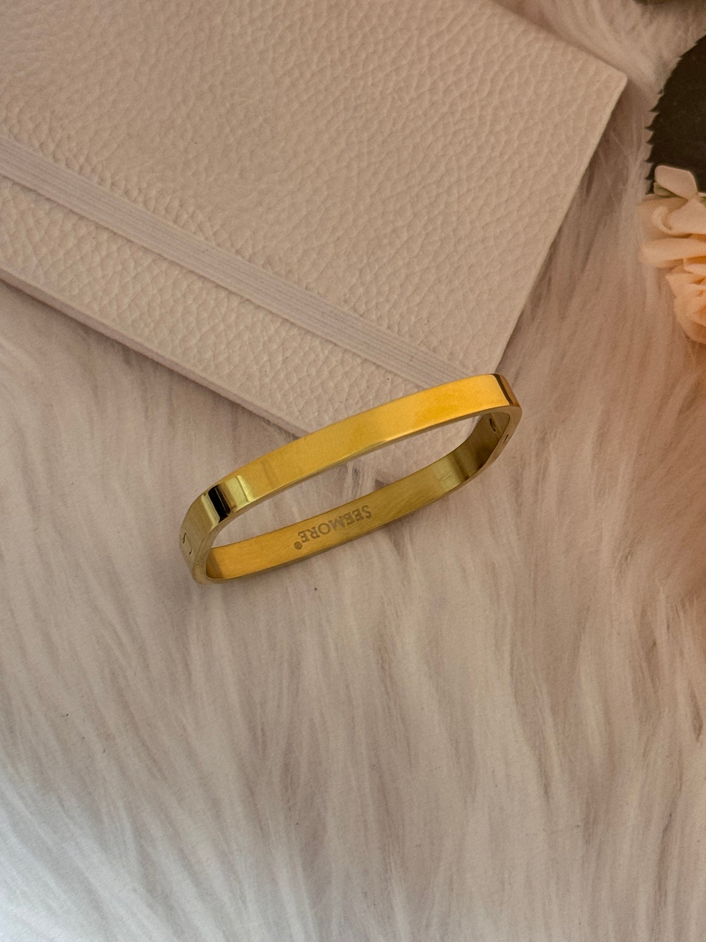 Gold bracelet on a textured beige surface