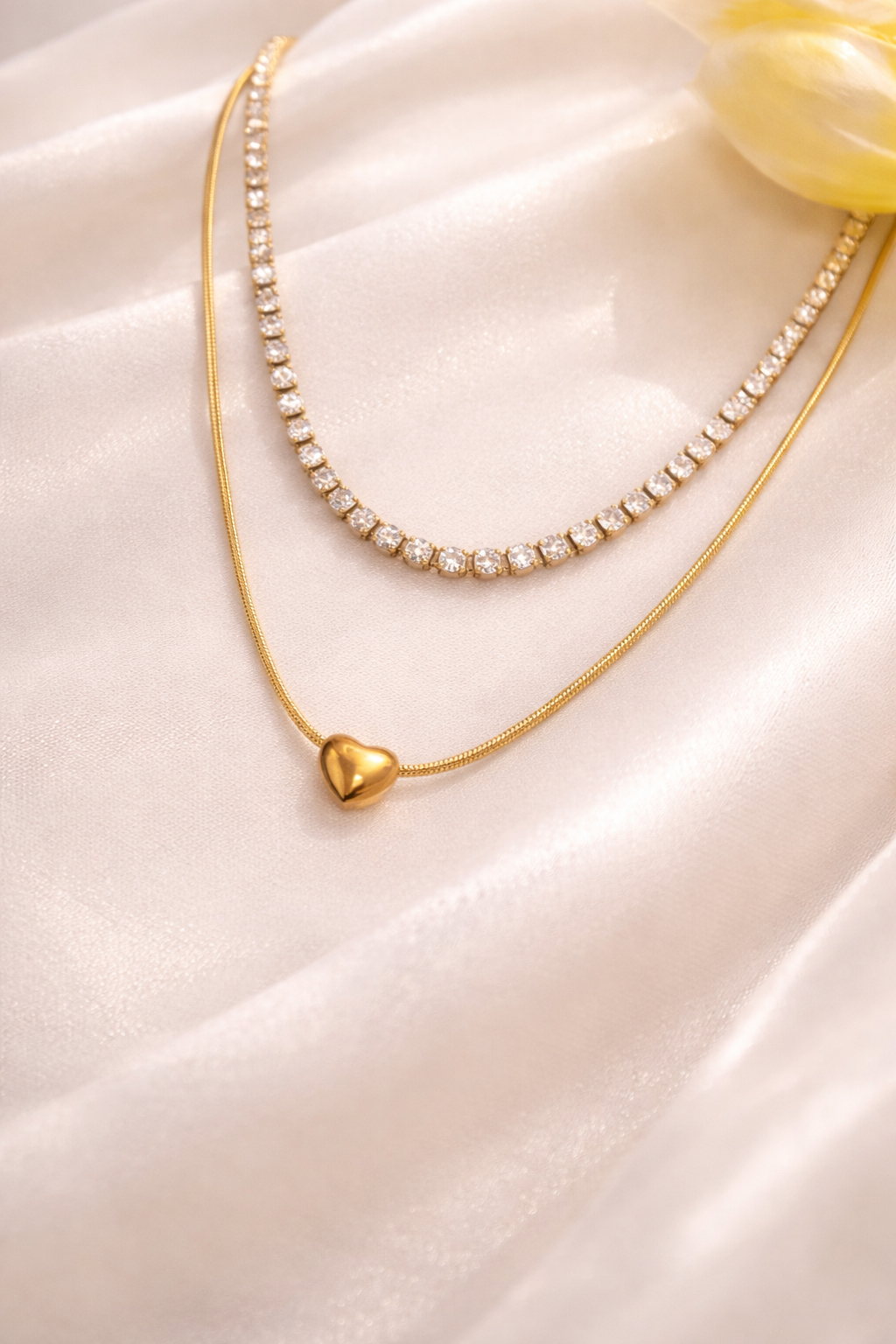 Gold necklace with a heart-shaped pendant on a white fabric background