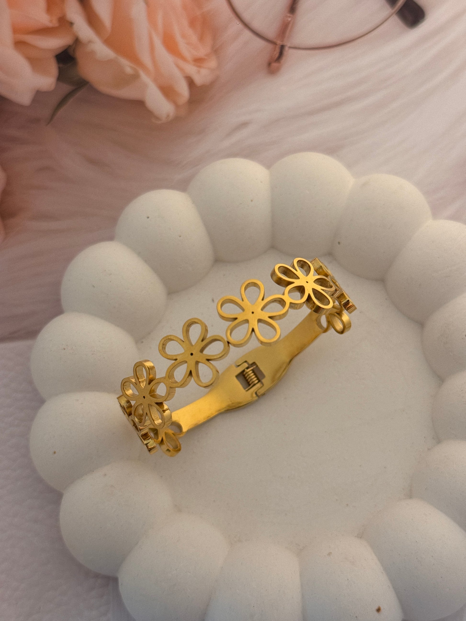 White beaded bracelet with gold flower-shaped clasp on a white background