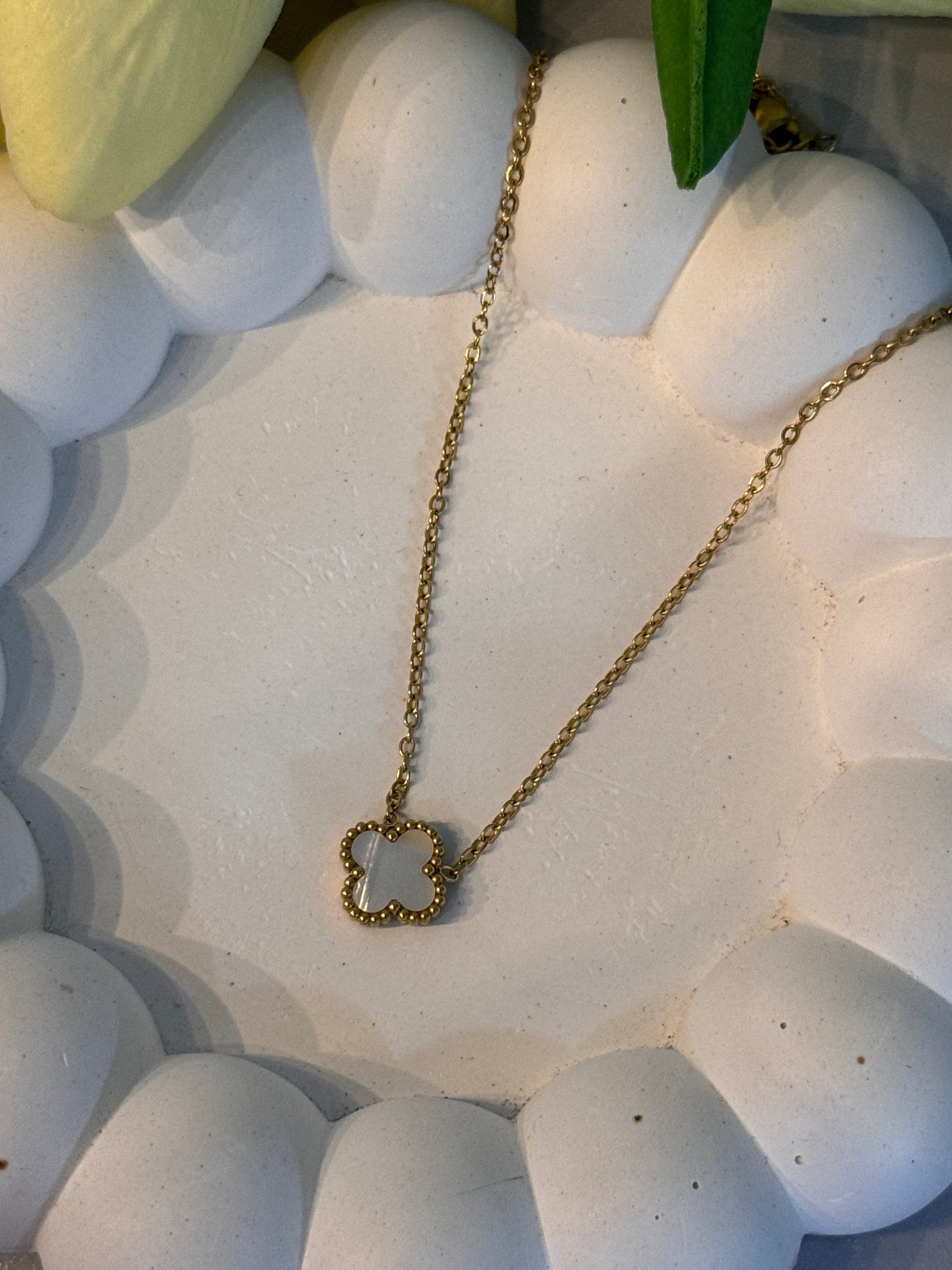 Gold necklace with a heart-shaped pendant on a textured white surface