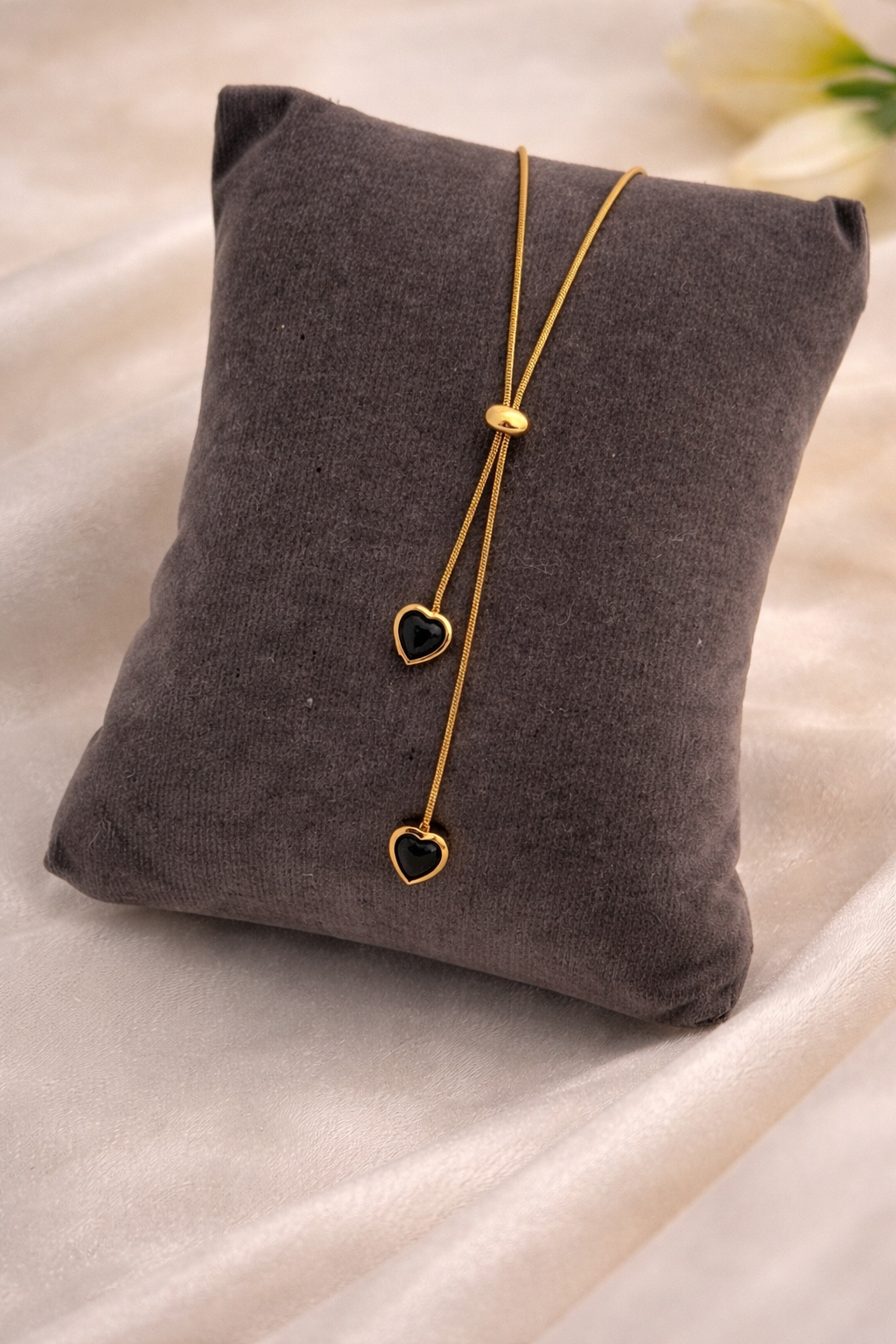 Gold necklace with heart pendants on a gray cushion