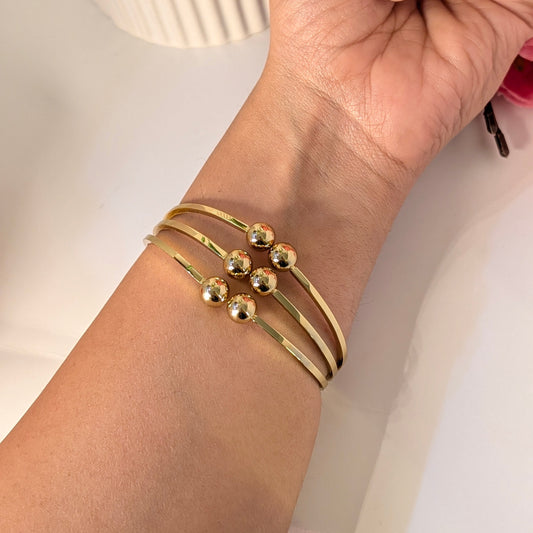 Gold bracelet on a wrist with a neutral background