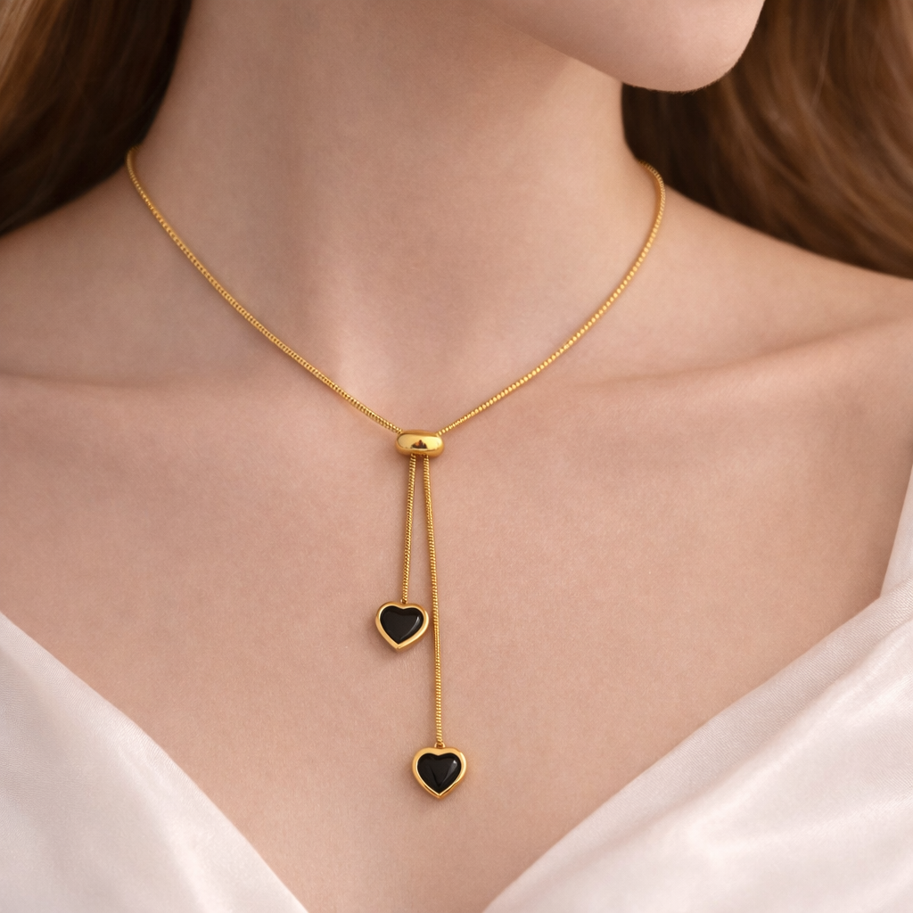 Gold necklace with heart-shaped pendants on a person wearing a white top.