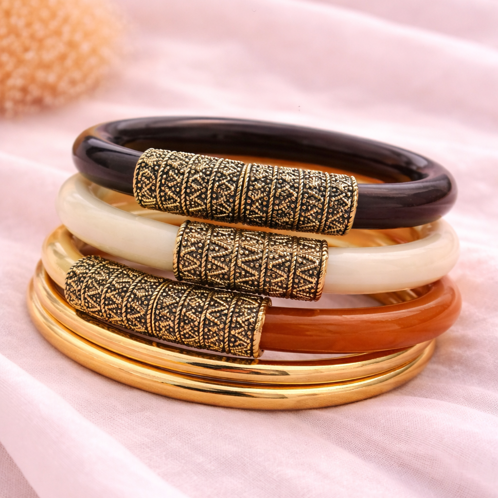Set of colorful bangles with gold and black patterns on a soft pink fabric background