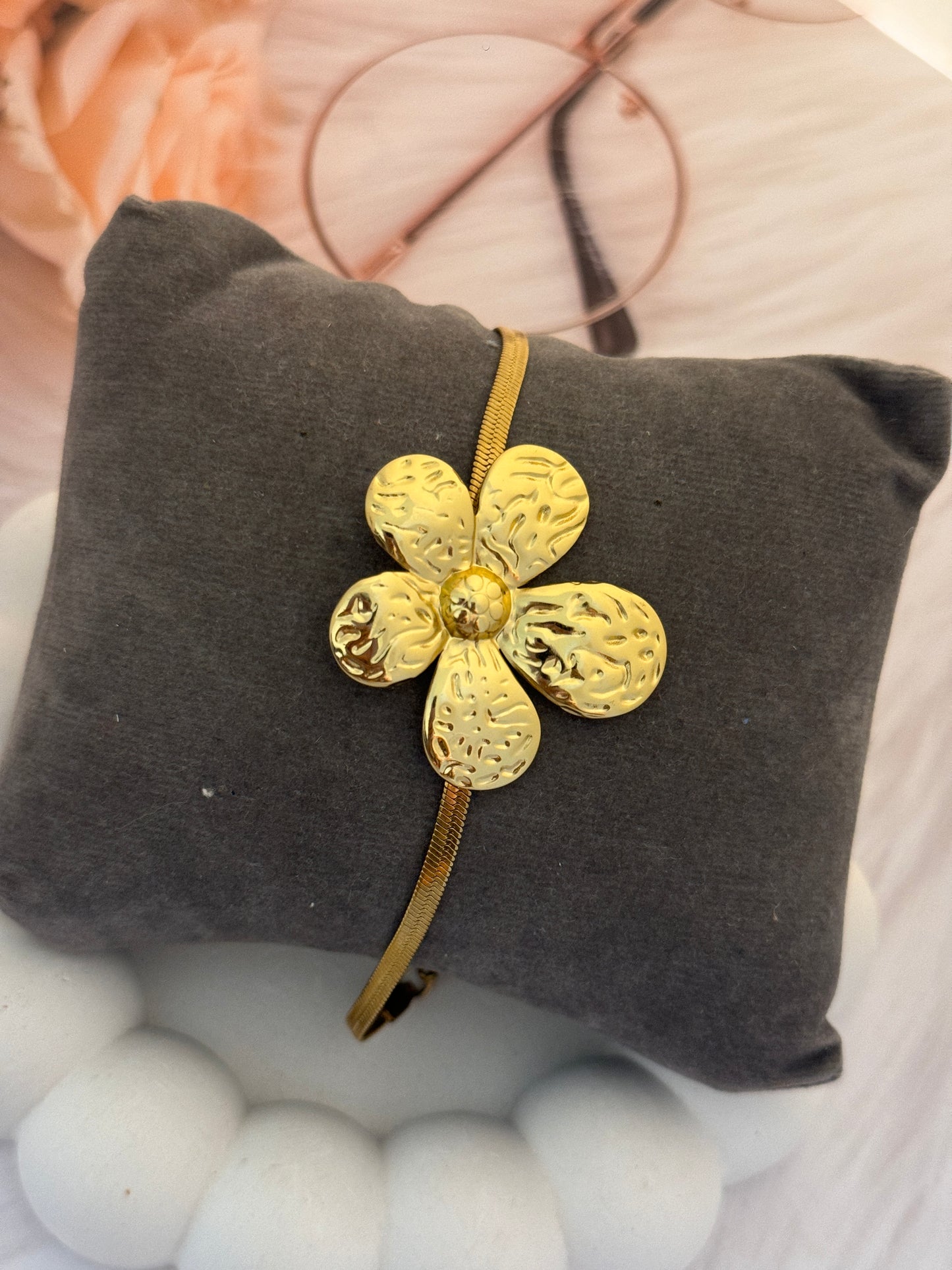 Gold flower-shaped hair clip on a gray cushion with a blurred background