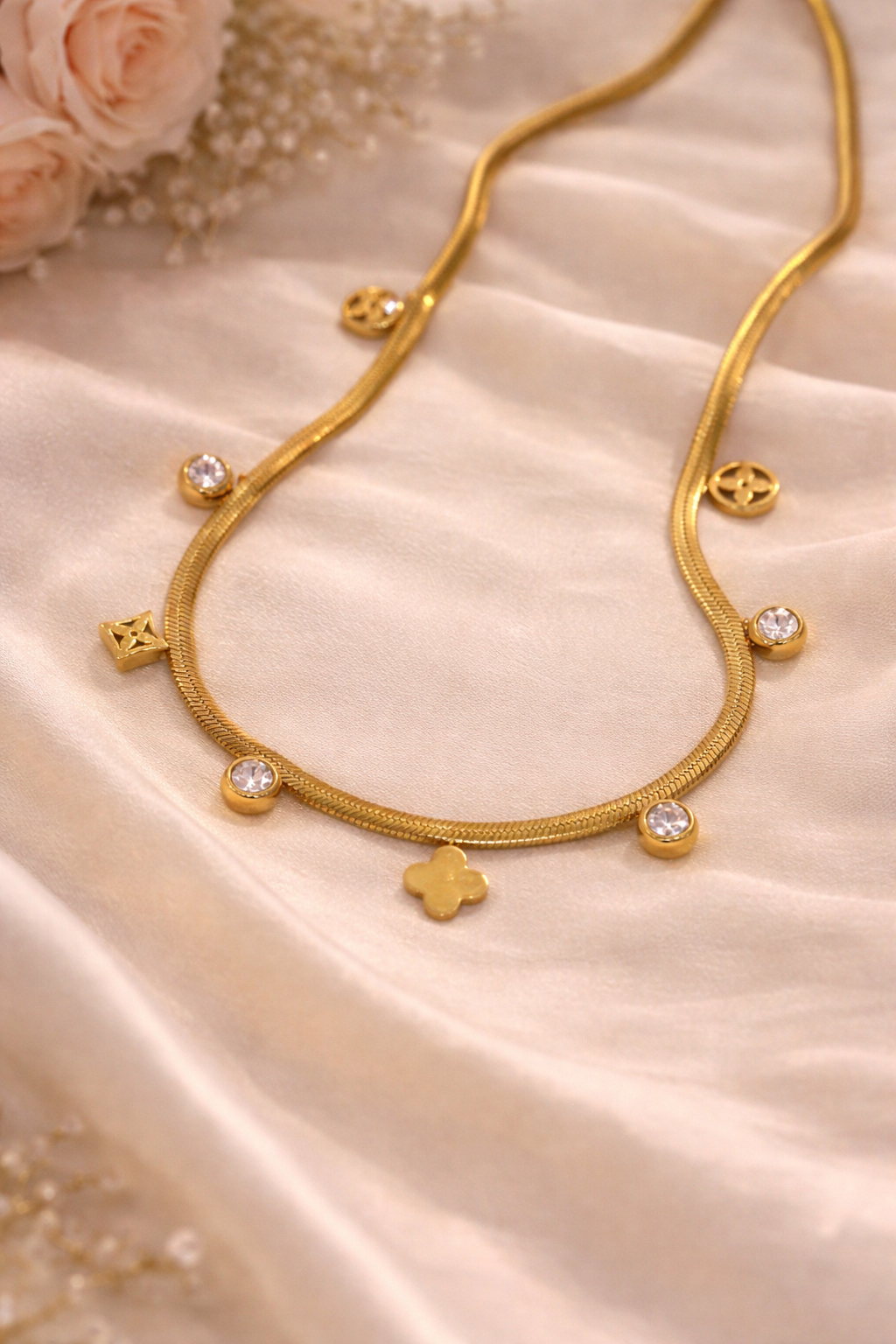 Gold necklace with heart and round pendants on a beige fabric background