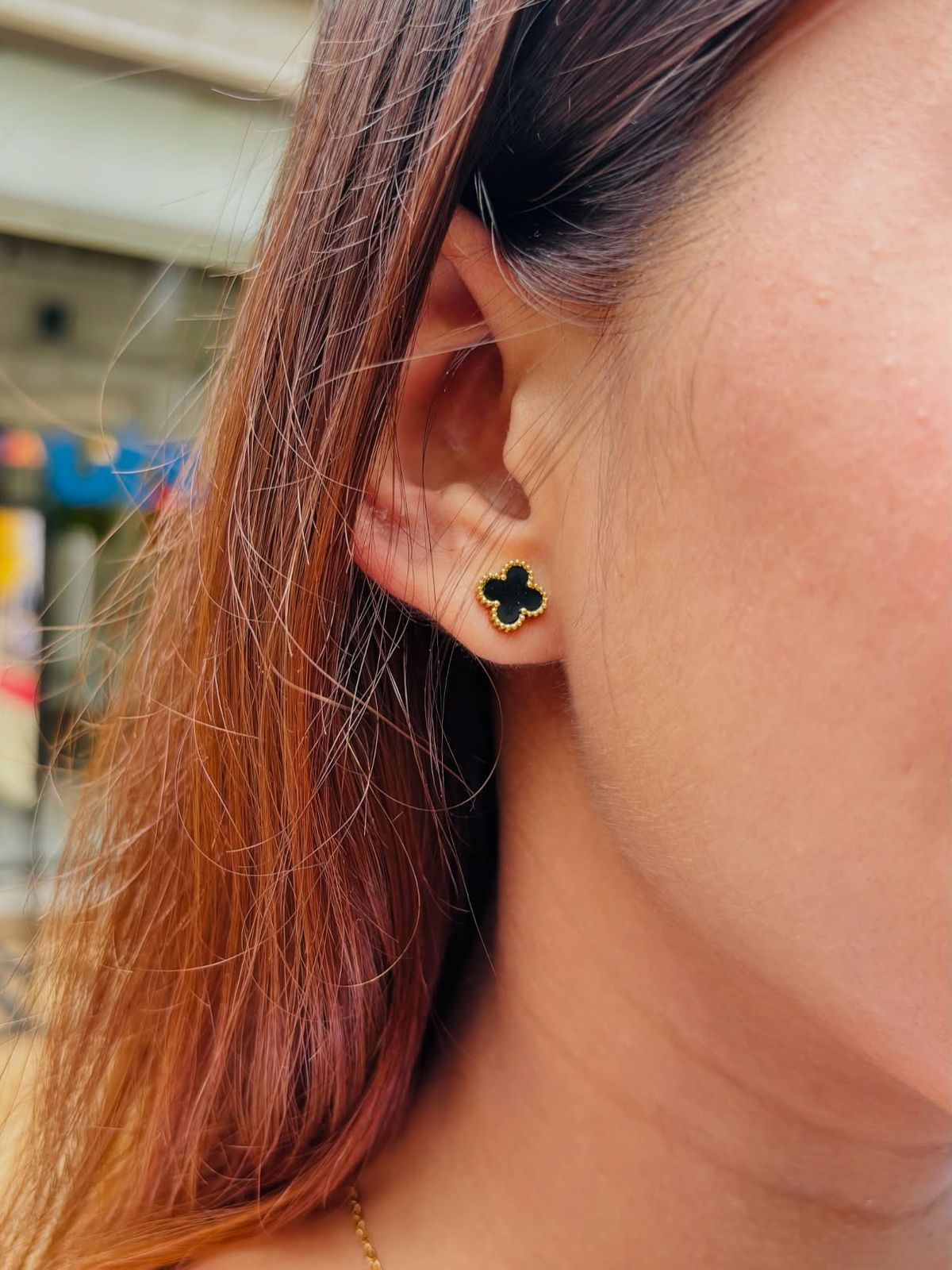Close-up of a person wearing a black clover-shaped earring.
