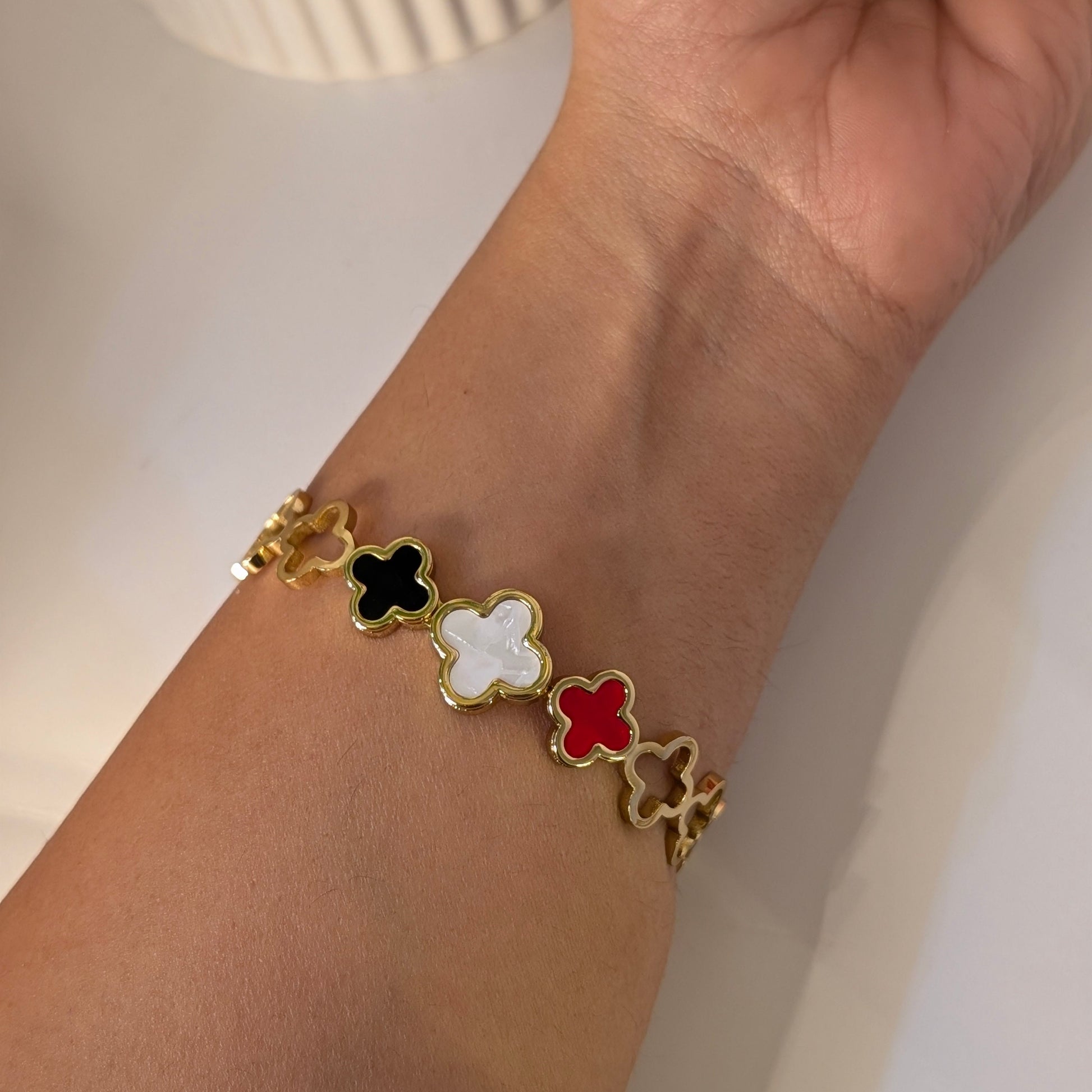 Bracelet with colorful clover-shaped charms on a wrist against a neutral background