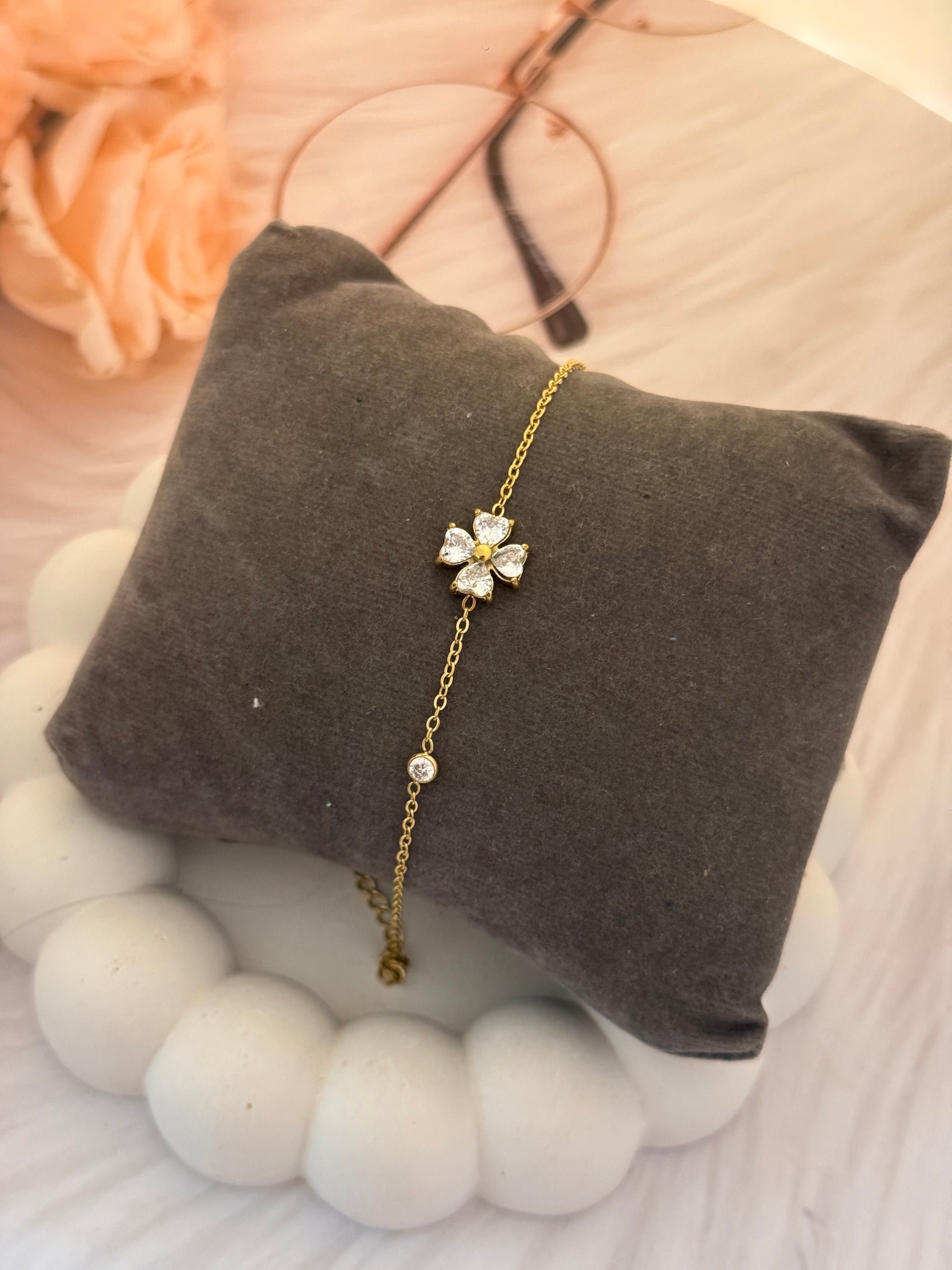 Gold bracelet with a floral clasp on a gray cushion, soft focus background