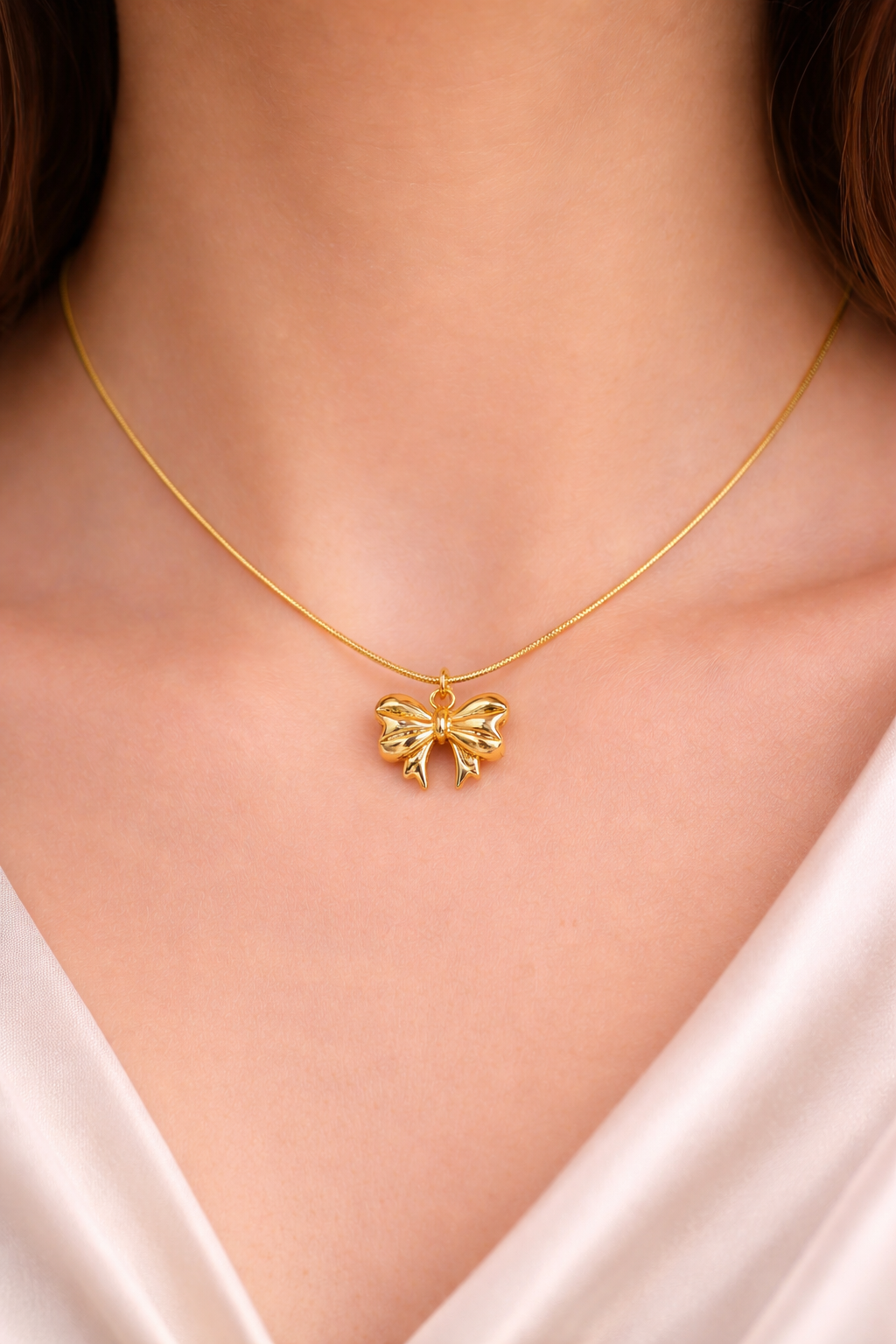 Gold necklace with a butterfly pendant on a person wearing a white top.