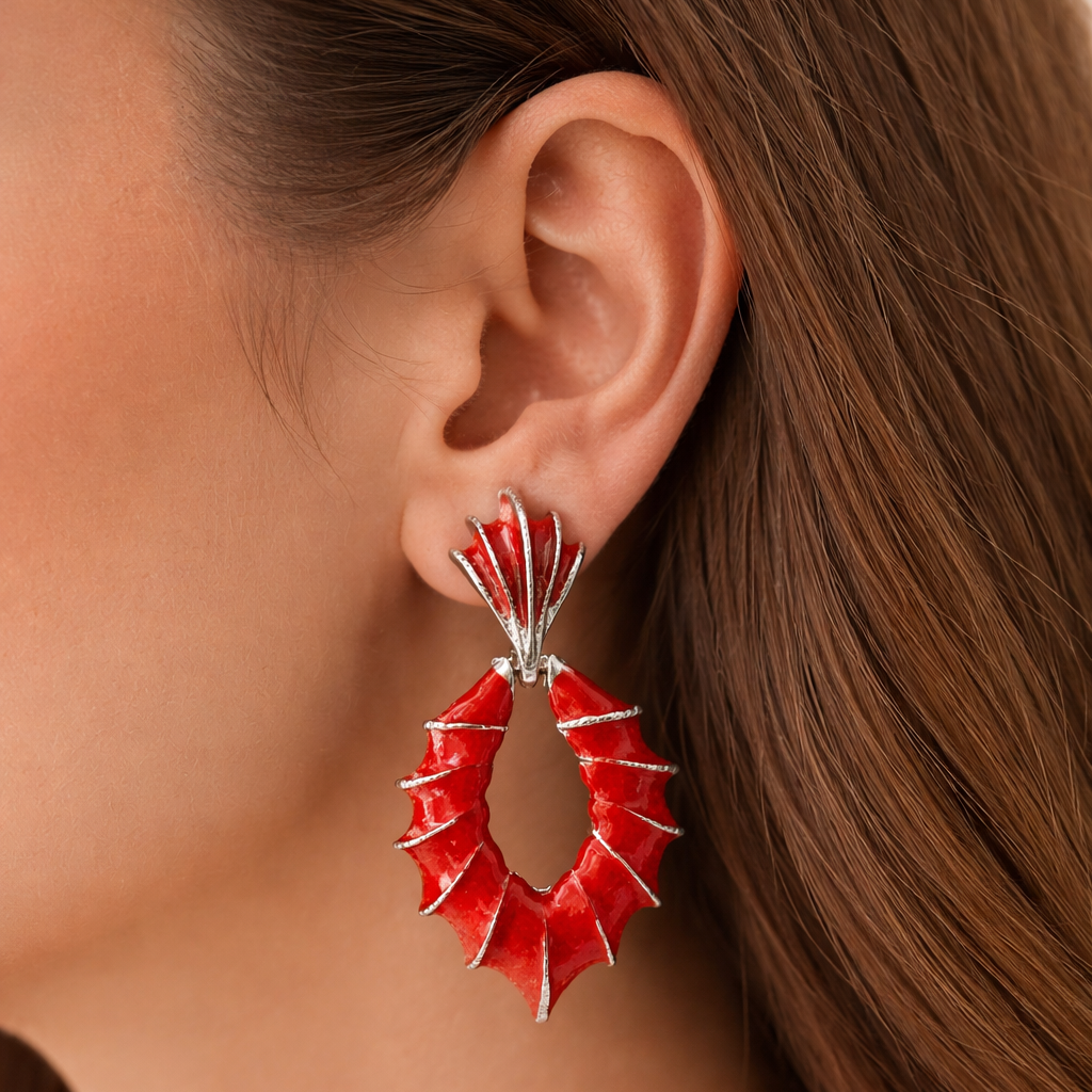 Close-up of a person wearing a red earrings with a silver setting.