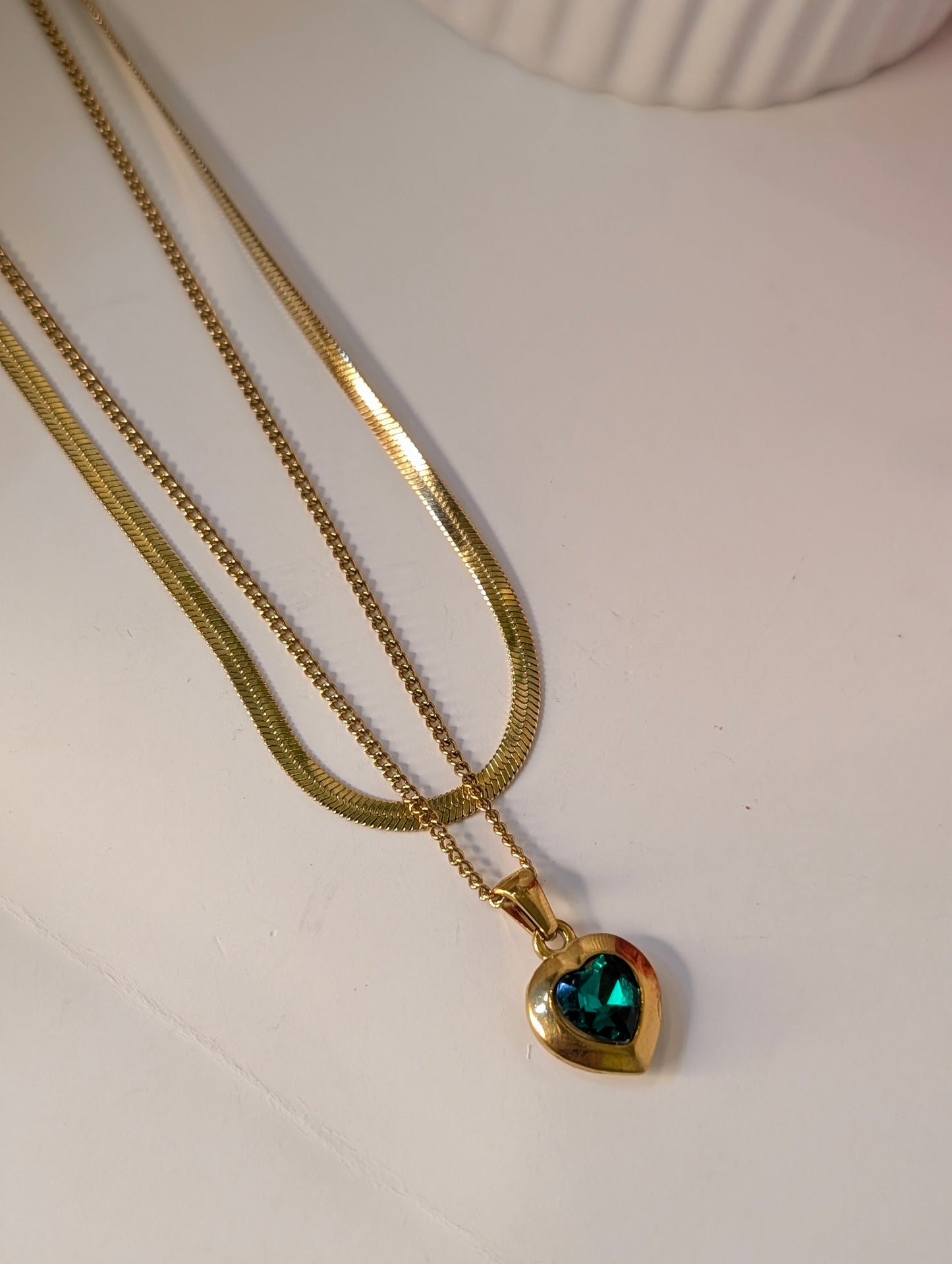 Gold necklace with a heart-shaped pendant on a white surface