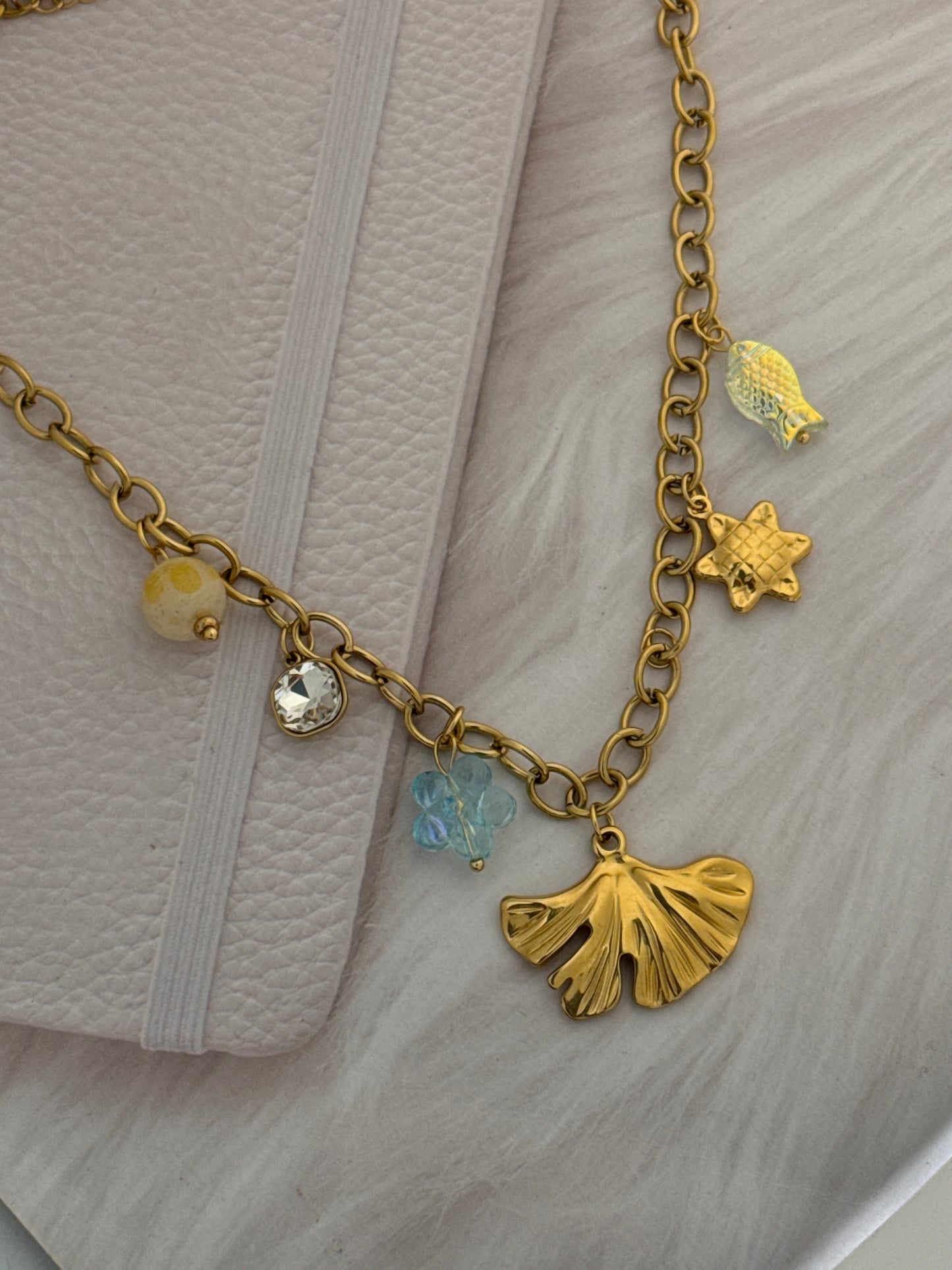 Gold bracelet with various charms on a textured surface