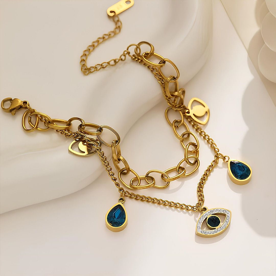 Gold bracelet with blue gemstone charms on a white background
