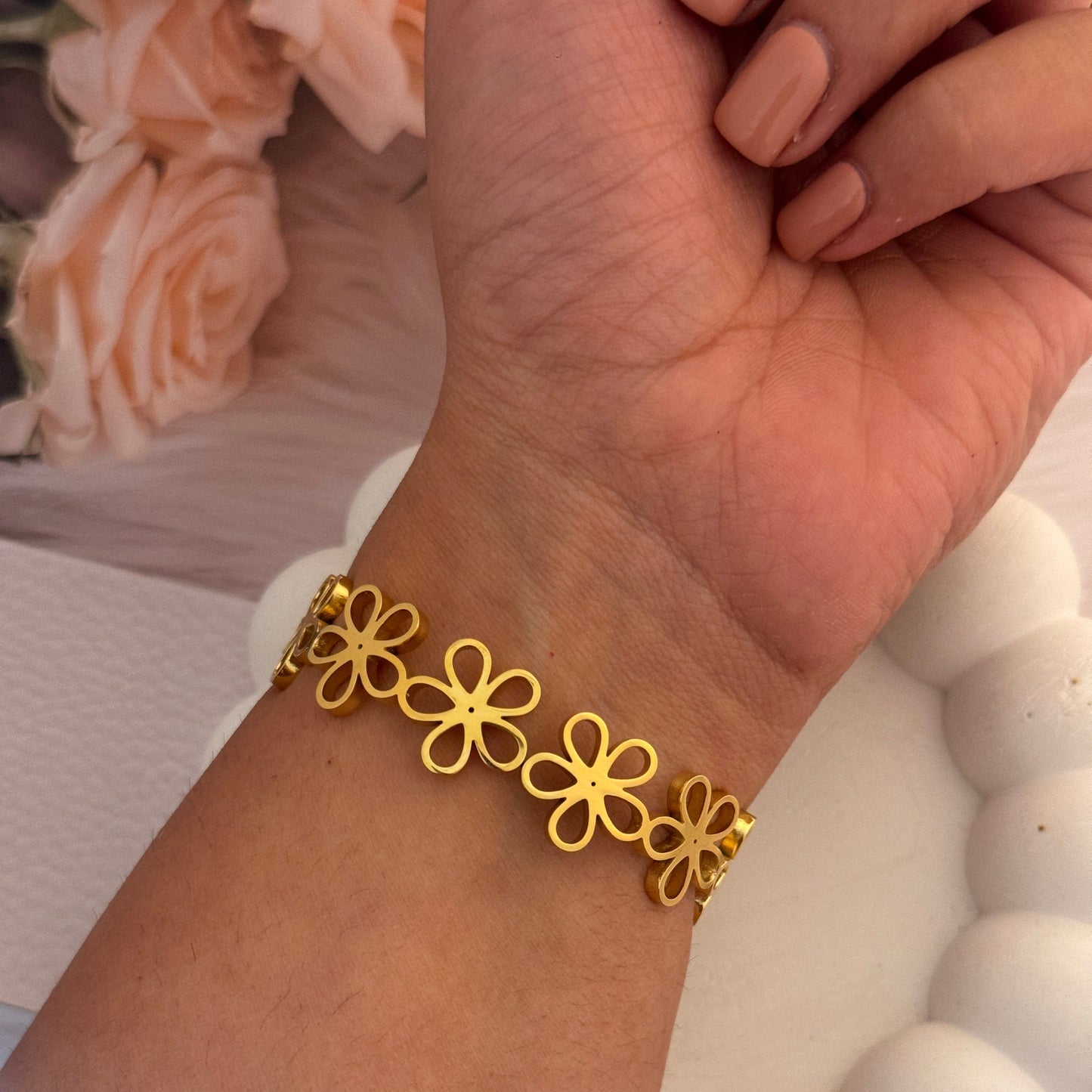 Gold floral bracelet on a wrist with a blurred background